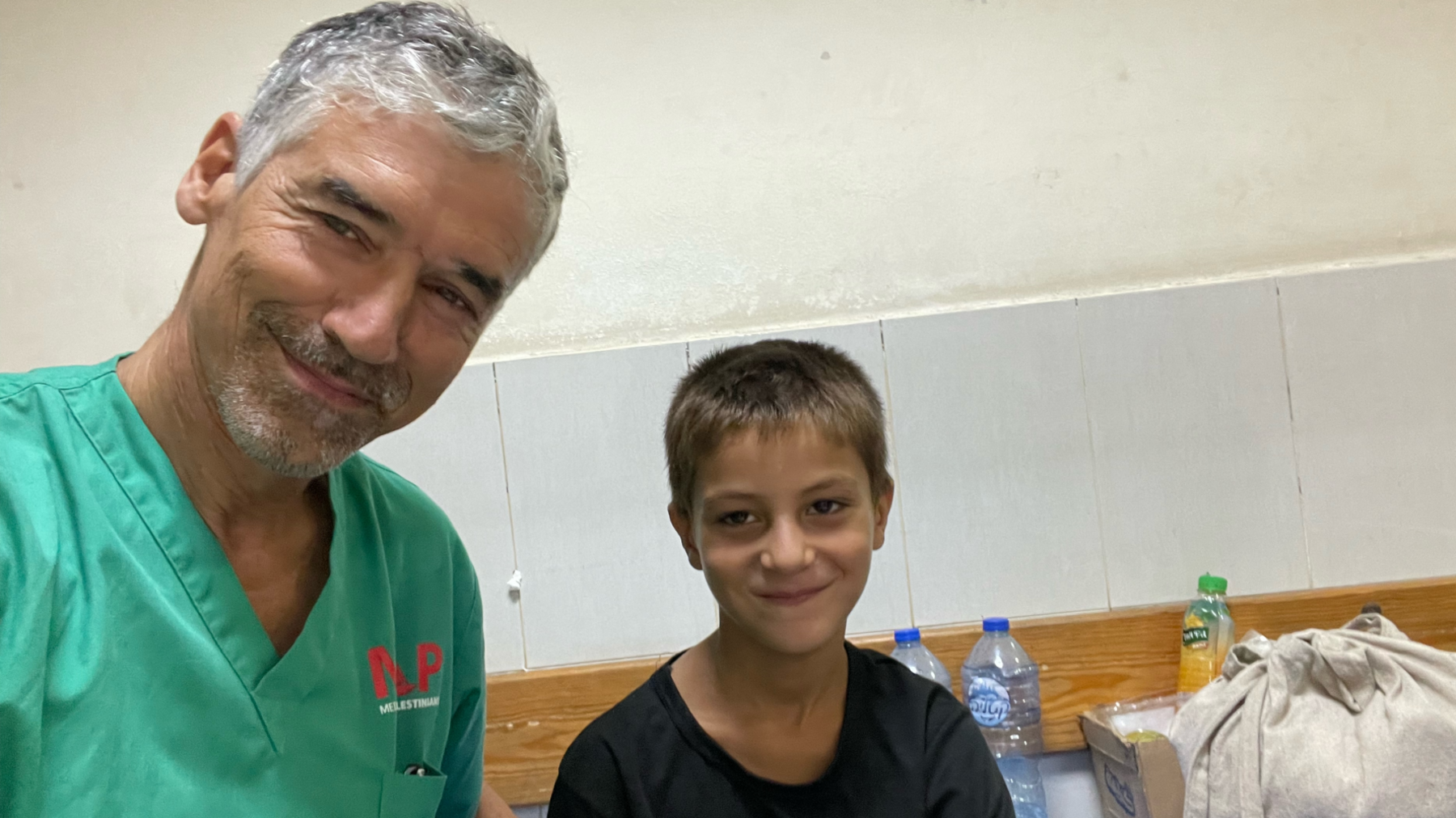 Prof Nizam Mamode, in green medical scrubs, poses next to Amer, a boy