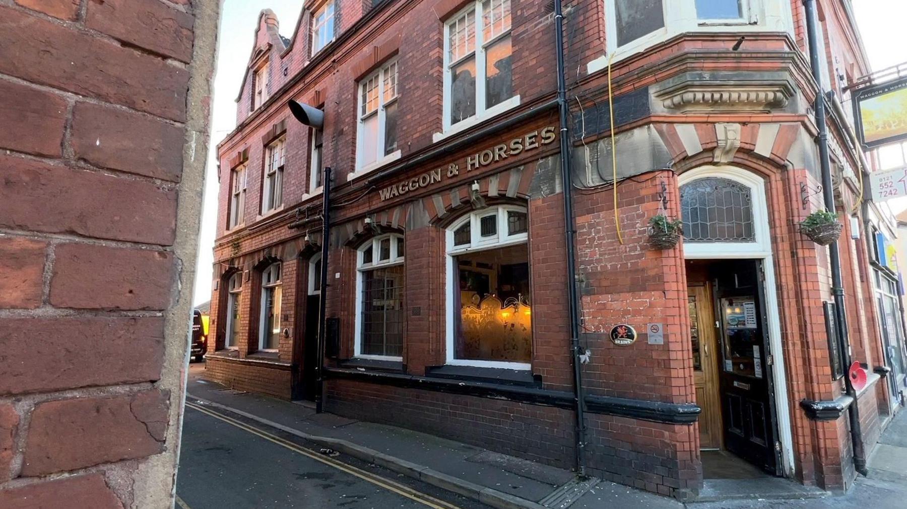 A large brick building with dozens of windows. The text Wagon & Horses is above the pub entrance.