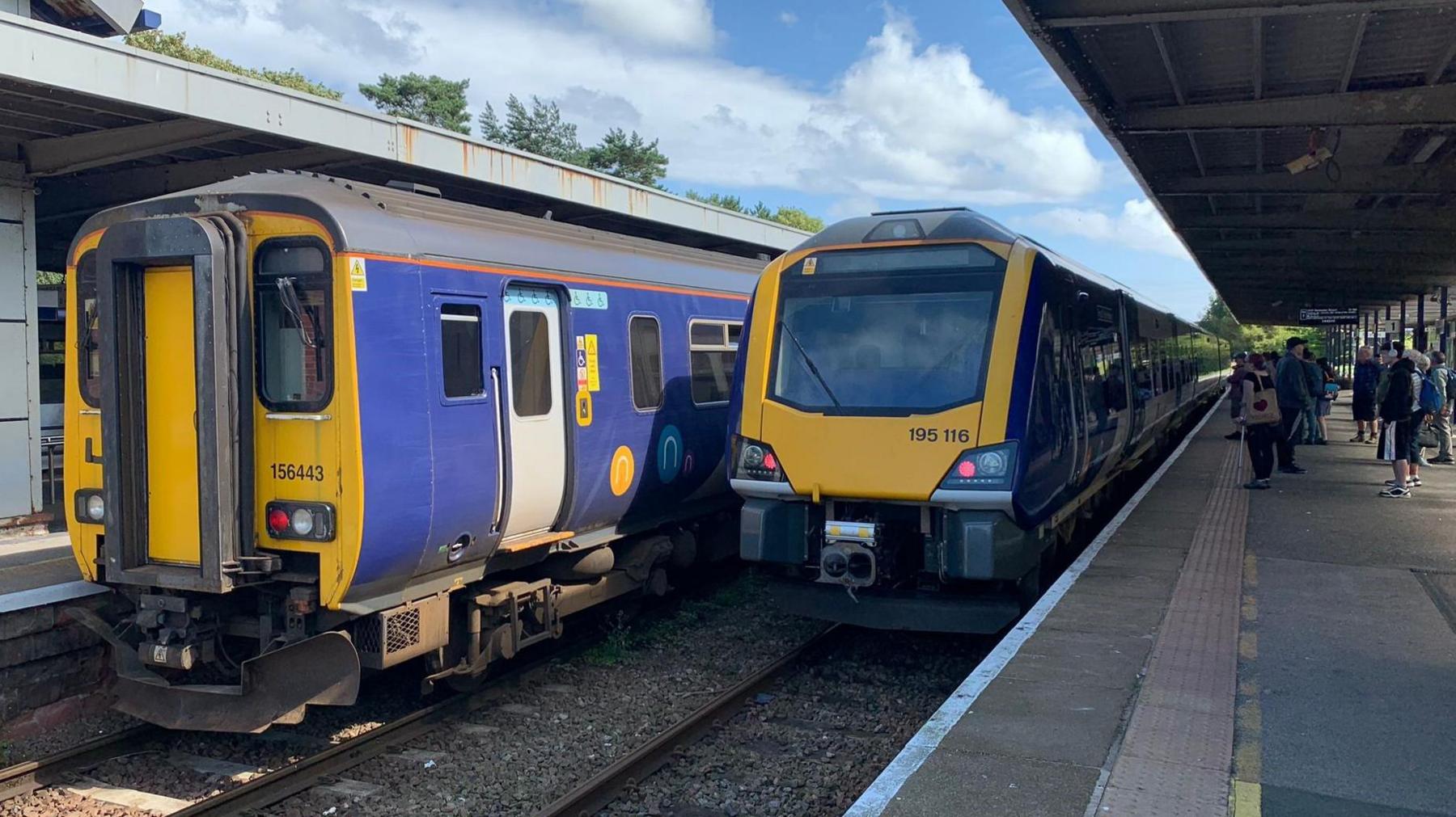 Two yellow and blue trains parked up at a railway platform.