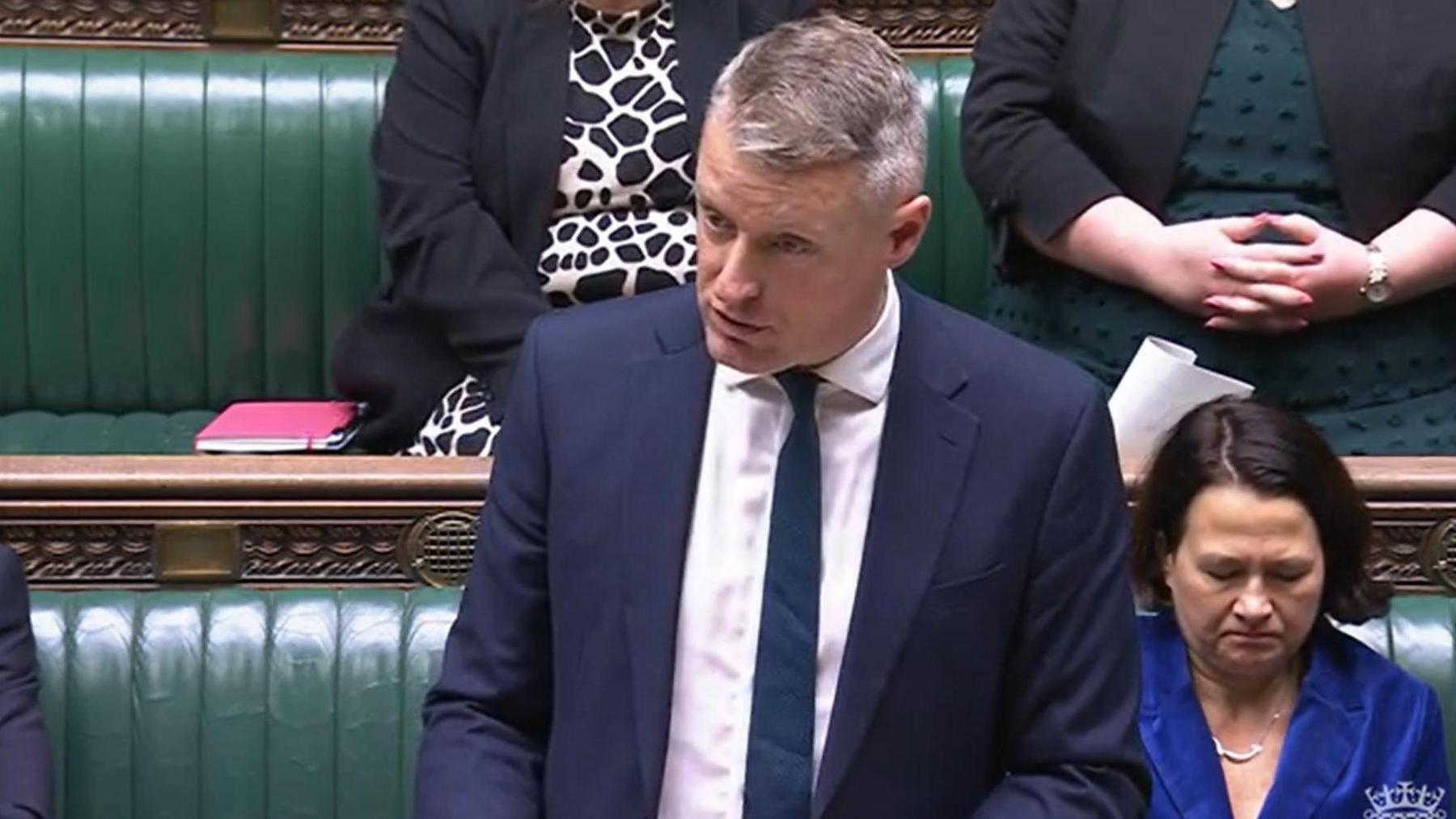 Luke Pollard wears a white shirt, blue tie and blue jacket and is standing at the despatch box