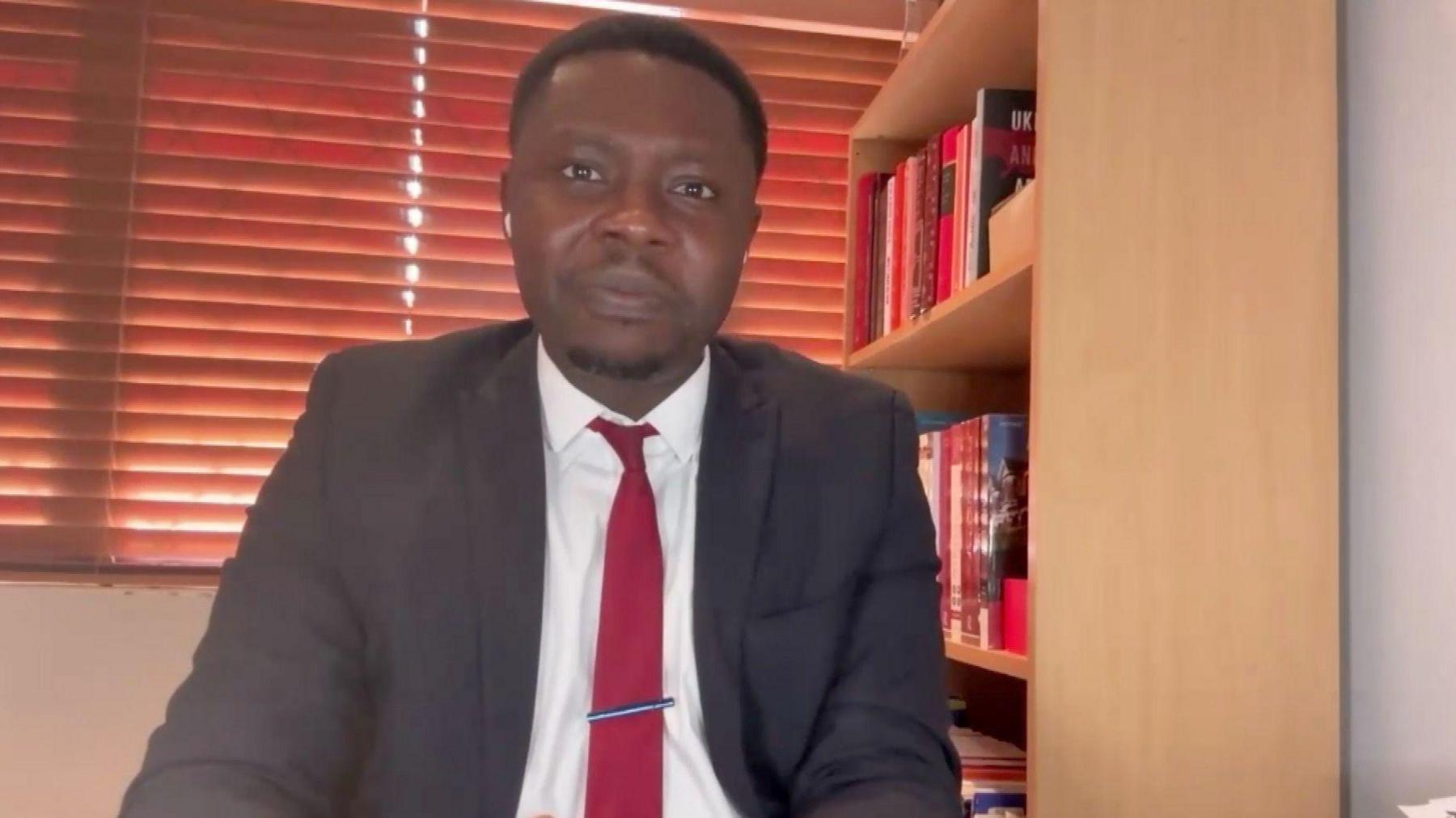 Immigration lawyer Clement Mensah sits at the desk in his office