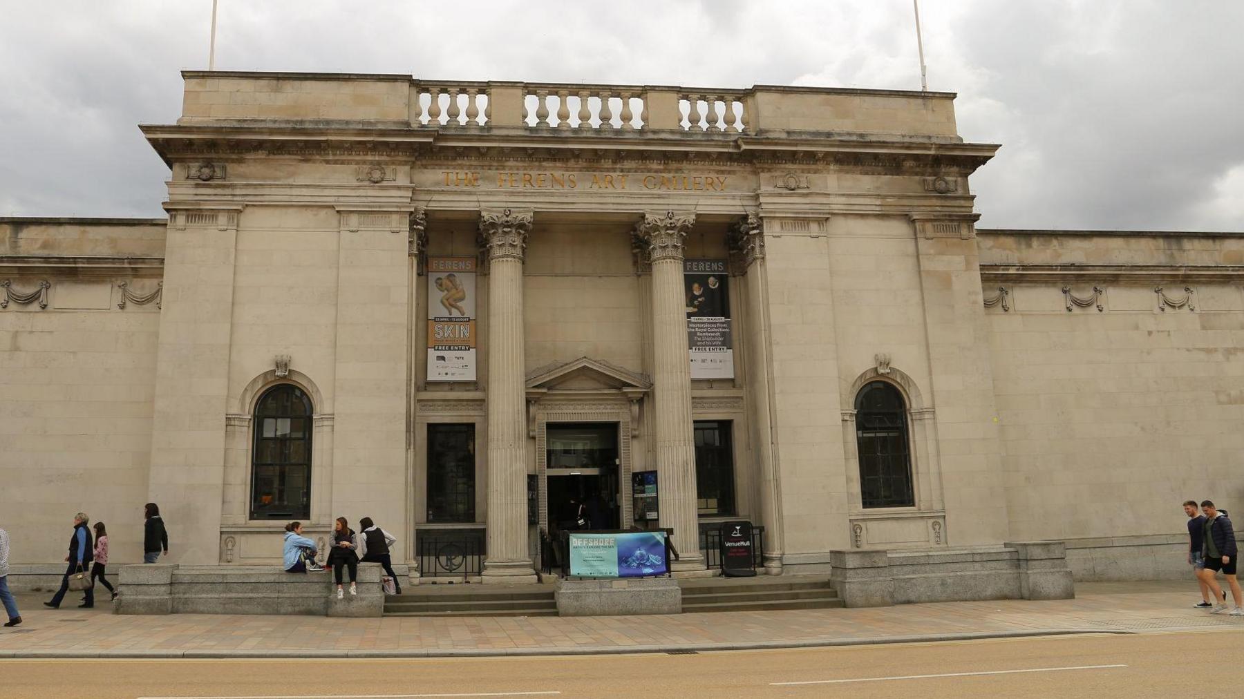 A stone-built, two-storey art gallery building in the neo-classical style, complete with Corinthian columns. Banners advertise exhibitions.