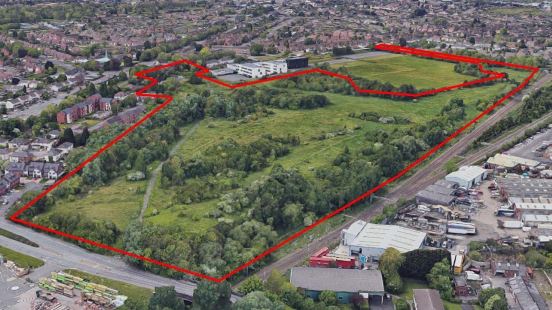 An aerial shot of the green space off Neachells Lane proposed for development. There is a red border outlining the land earmarked for the distribution centre with homes and buildings around the marked area.