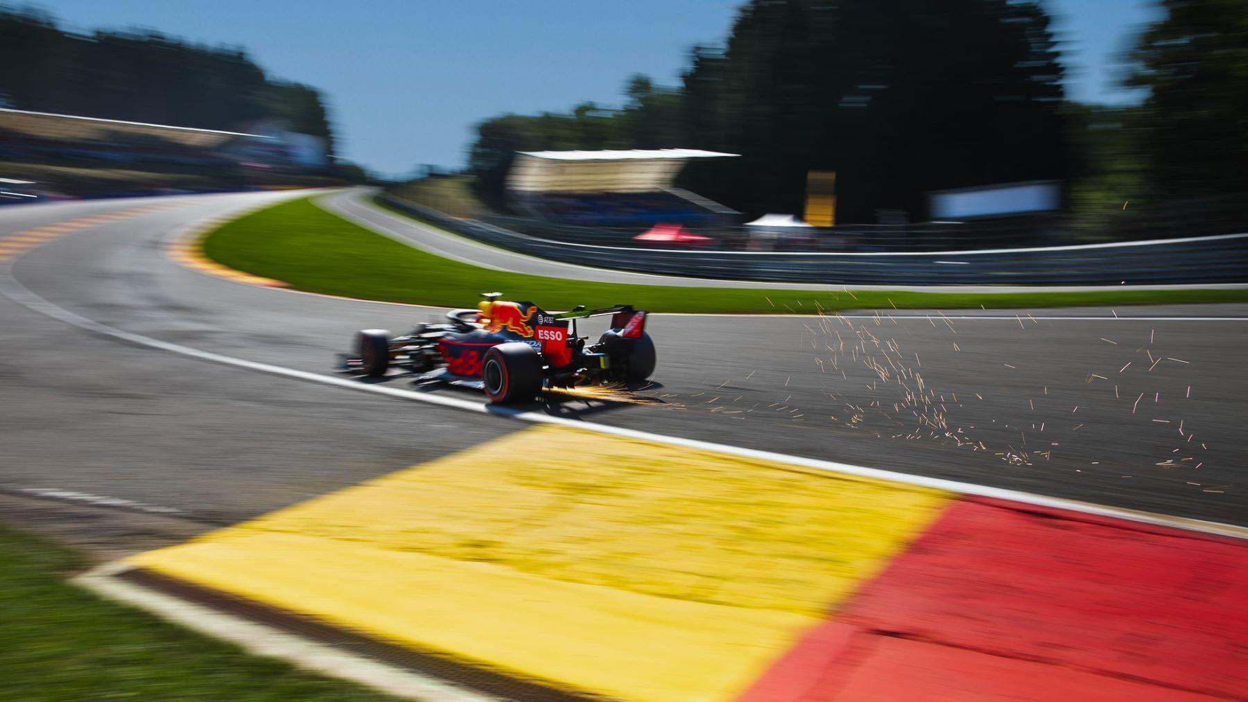 Driver Alex Albon heading around a corner in a black and red Formula 1 car as sparks fly out of the back