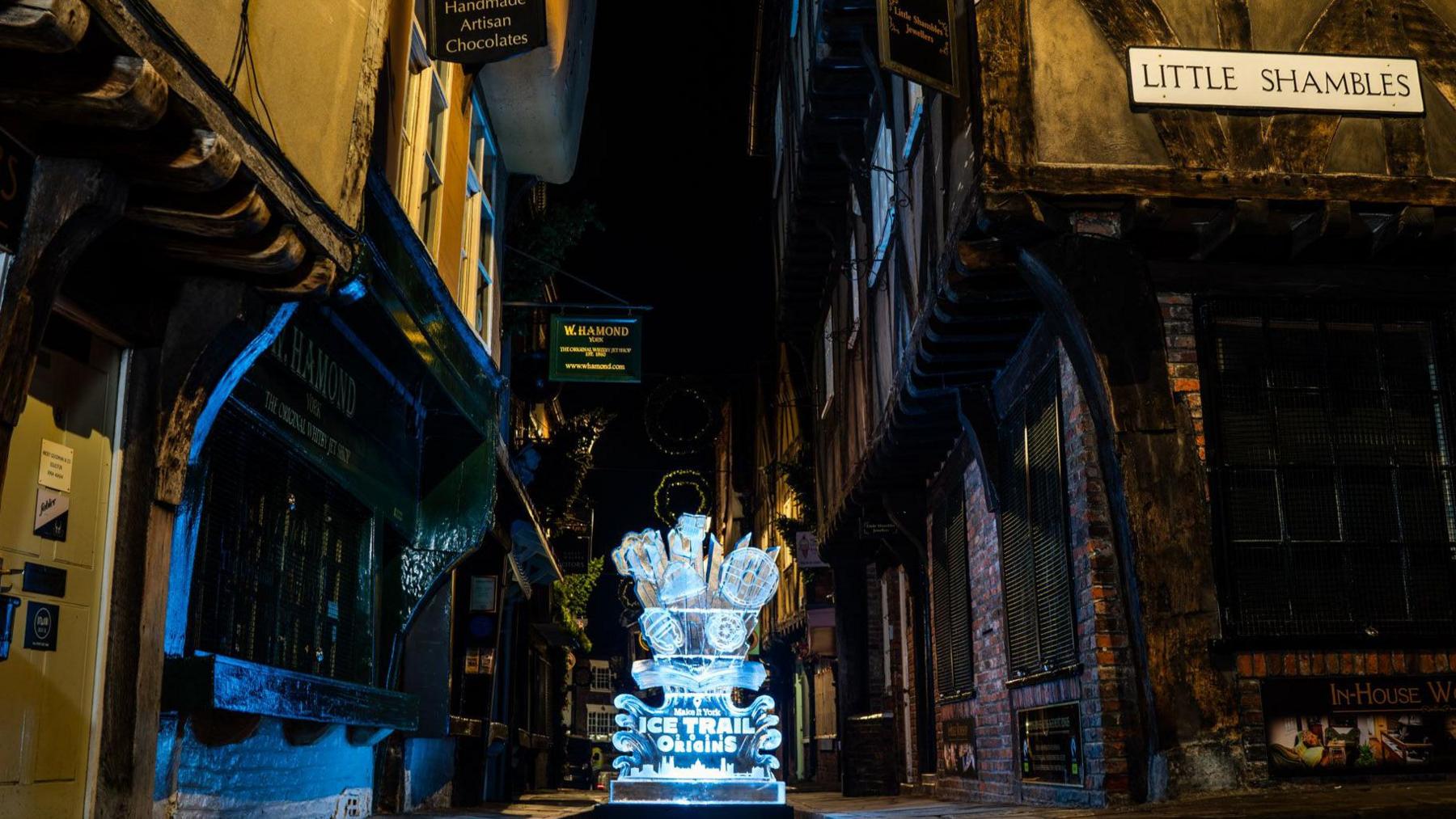 View of the Shambles with tudor-framed buildings with a sign on the right hand side stating Little Shambles, with an ice sculputre in the centre of the street