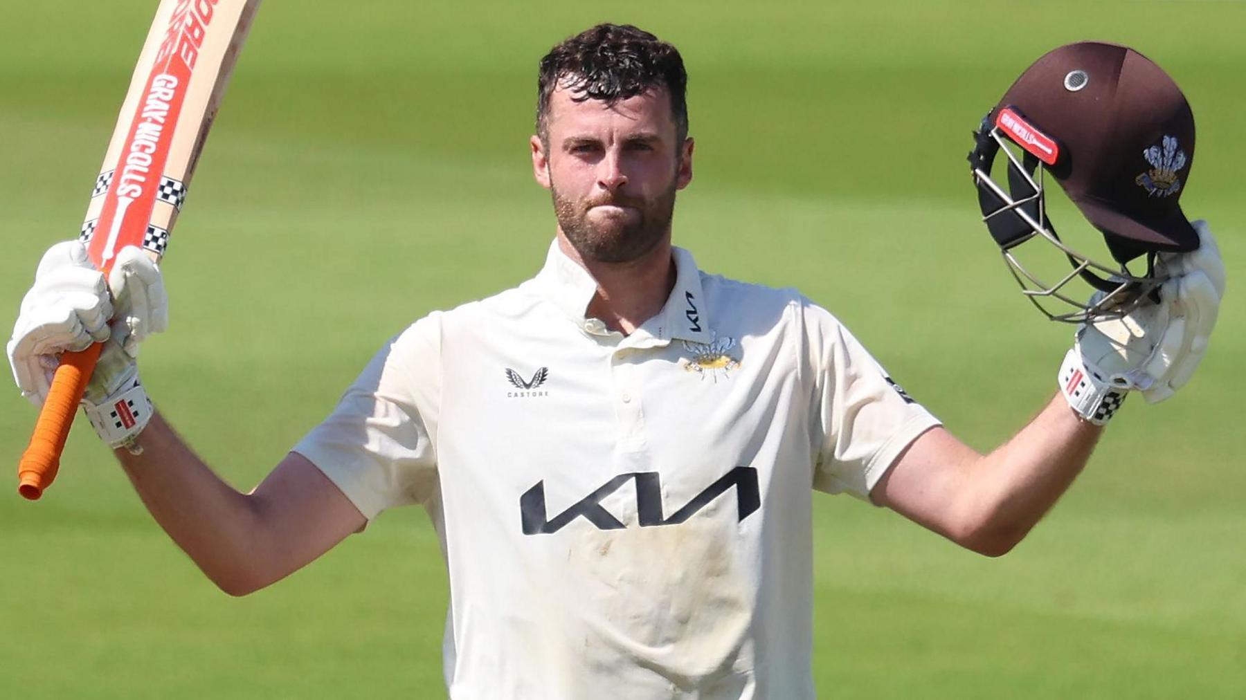 Dom Sibley of Surrey holds up his bat in his right and brown Surrey helmet in his left has celebrates scoring 300 runs during the County Championship match between against Durham