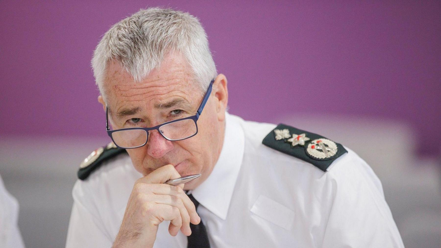 A man with grey hair and glasses in a police uniform