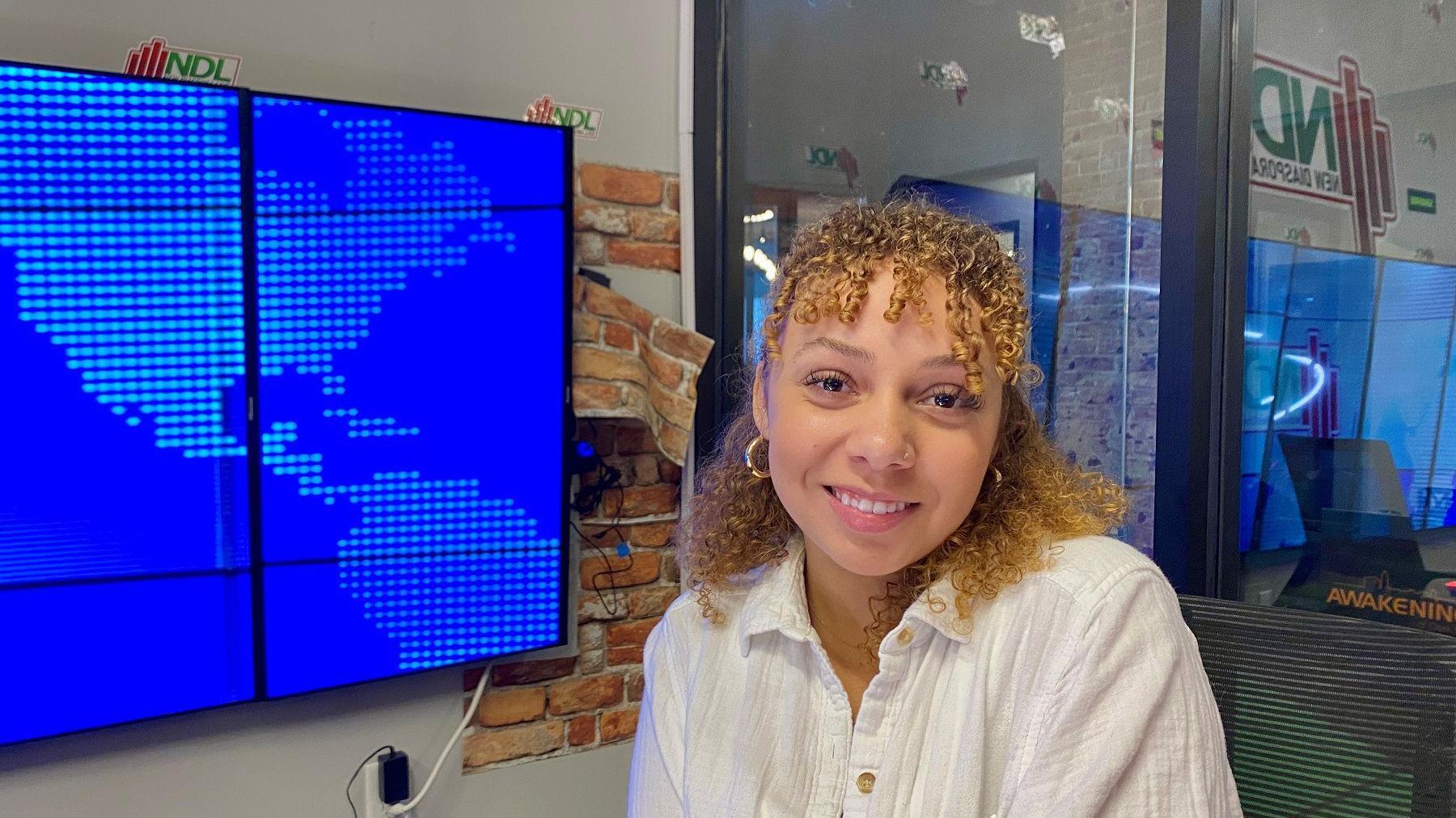 Laura Koveleski  smiles in front of a screen displaying a map of North America.