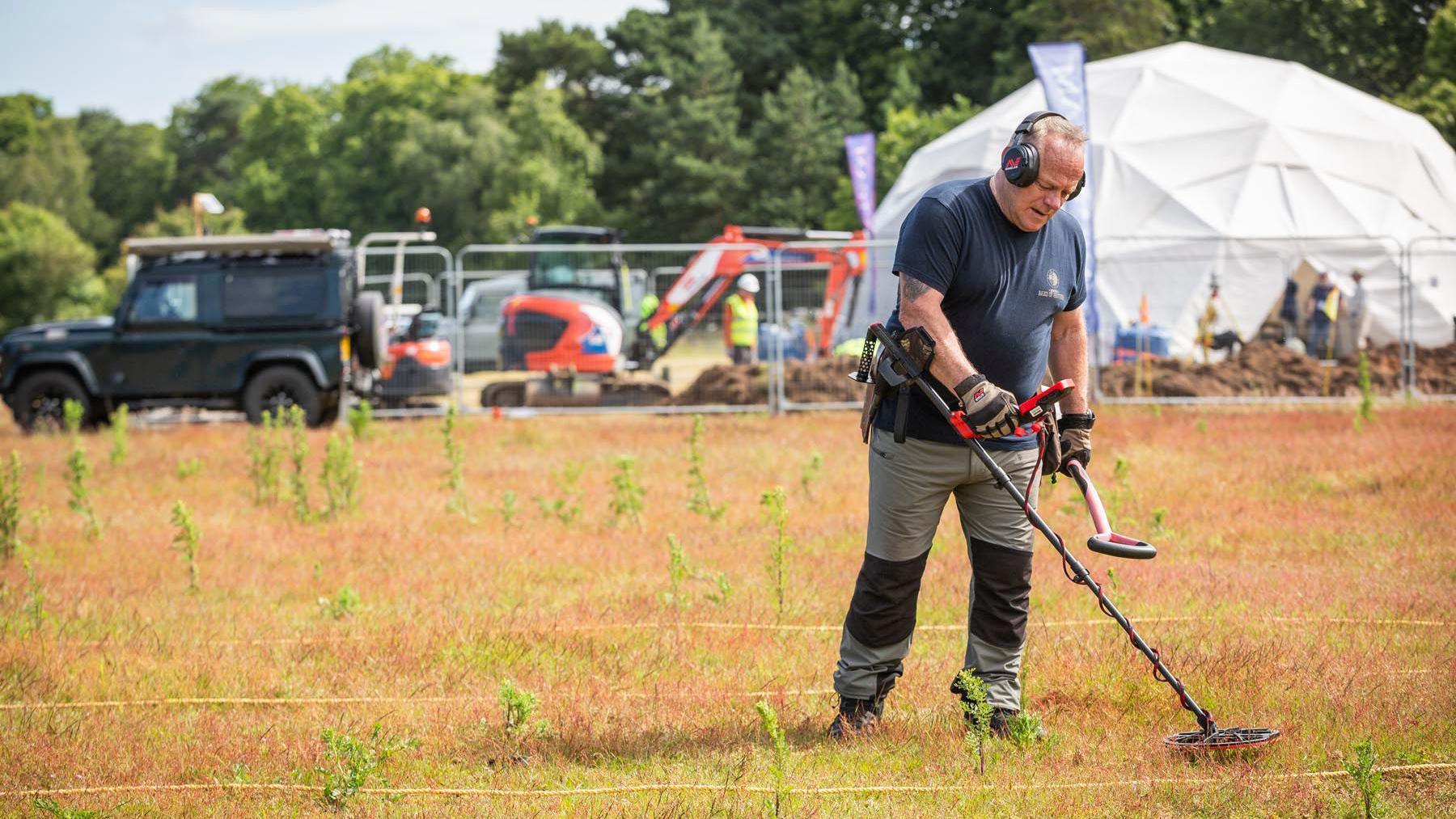 A metal detectorist in a field in Sutton Hoo, Sufflk