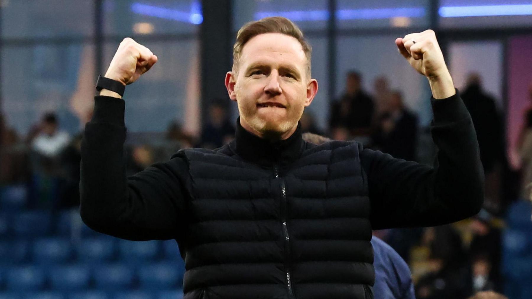 Shrewsbury Town head coach Gavin Cowan holds both fists up in the air in celebration