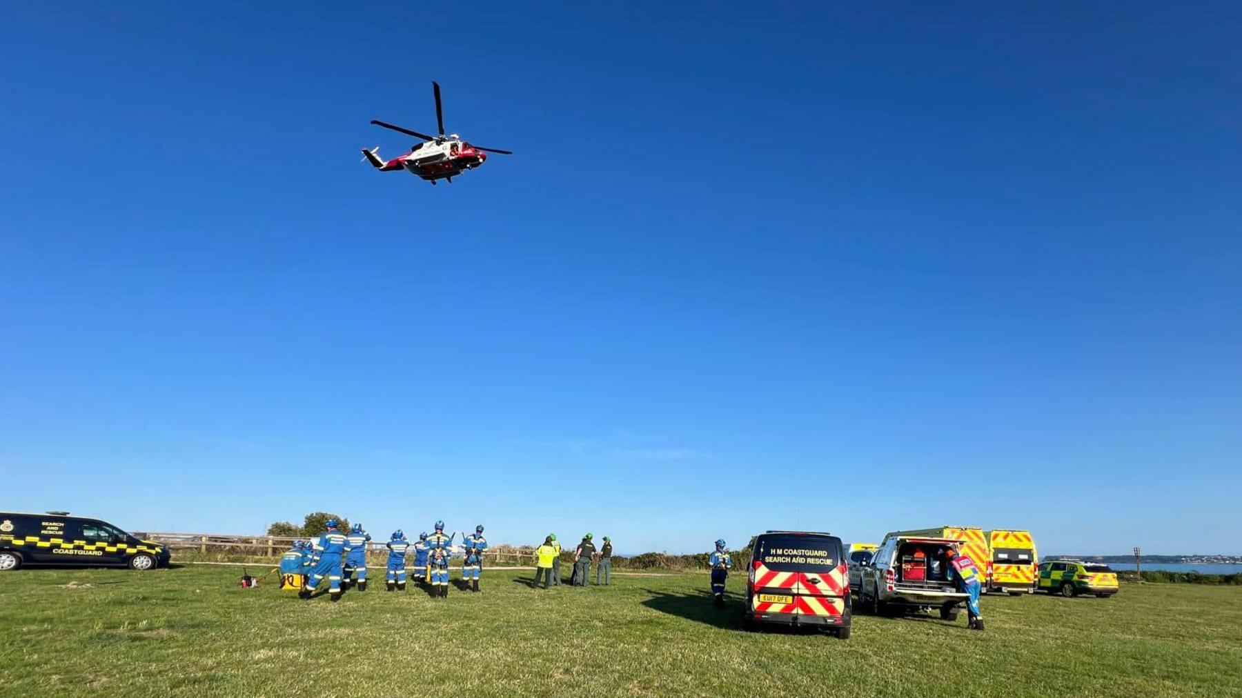 A coastguard helicopter and coastguard teams attending the rescue scene near the cliff fall in Daddyhole