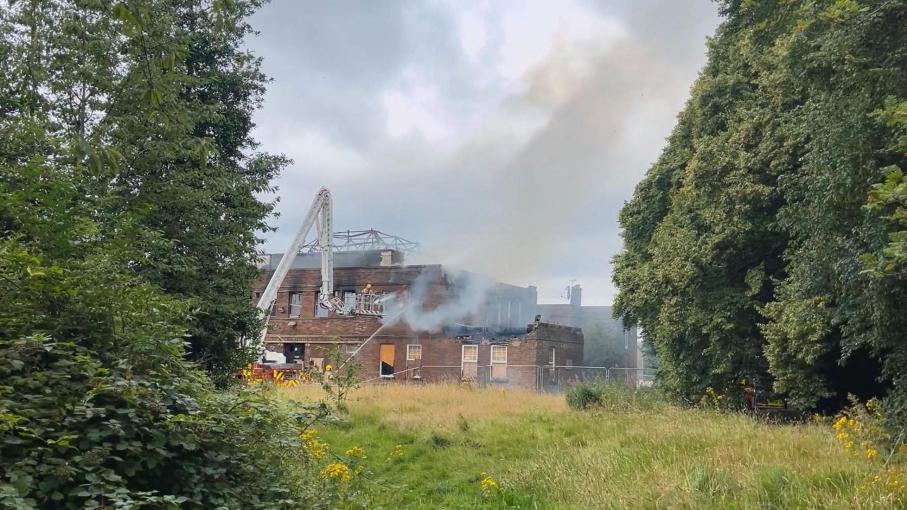 Firefighters using a cherry picker to extinguish the blaze at the derelict working men's club.