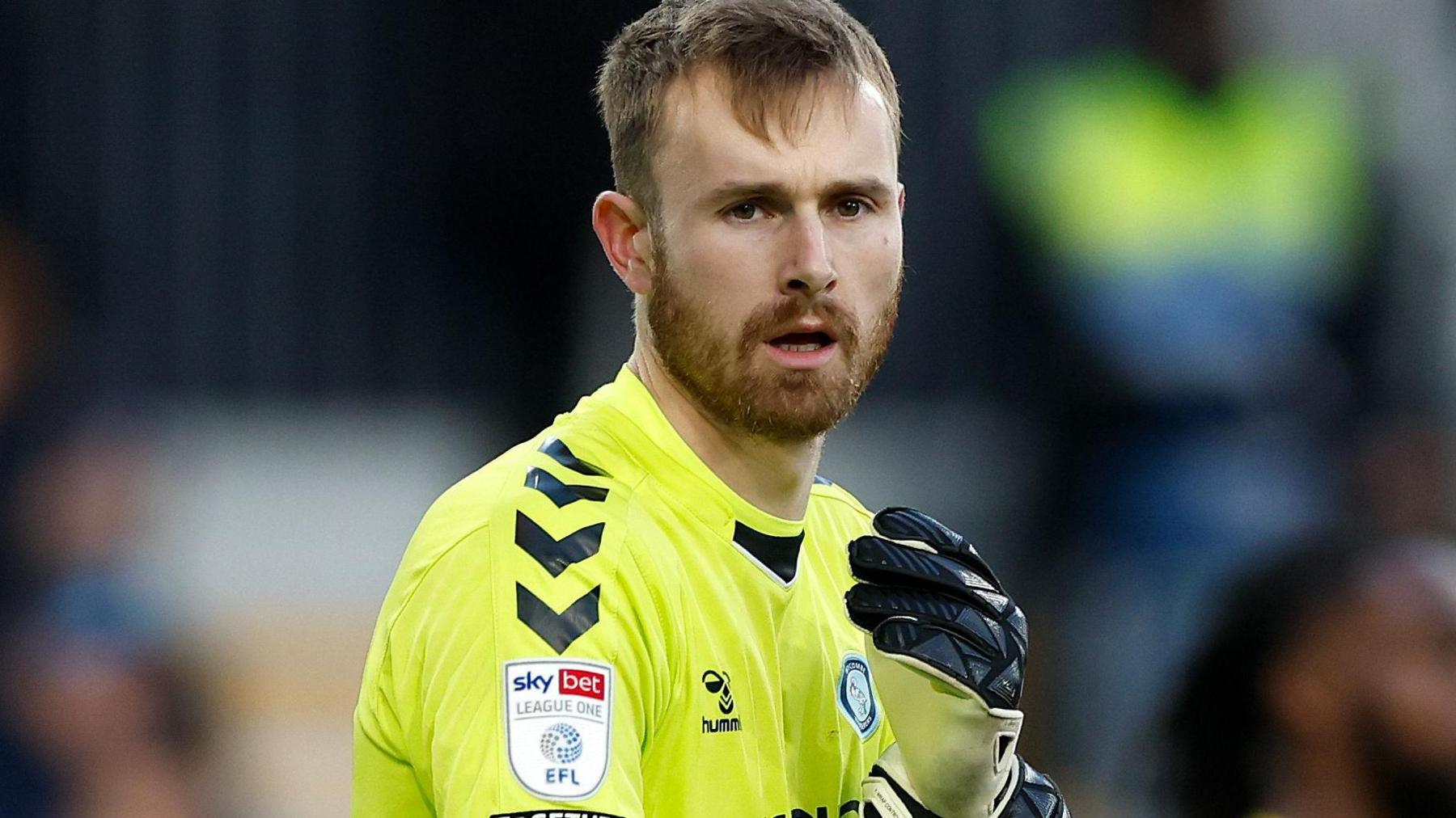 Goalkeeper Will Norris in action for Wycombe in the 2025-26 season wearing a florescent yellow jersey
