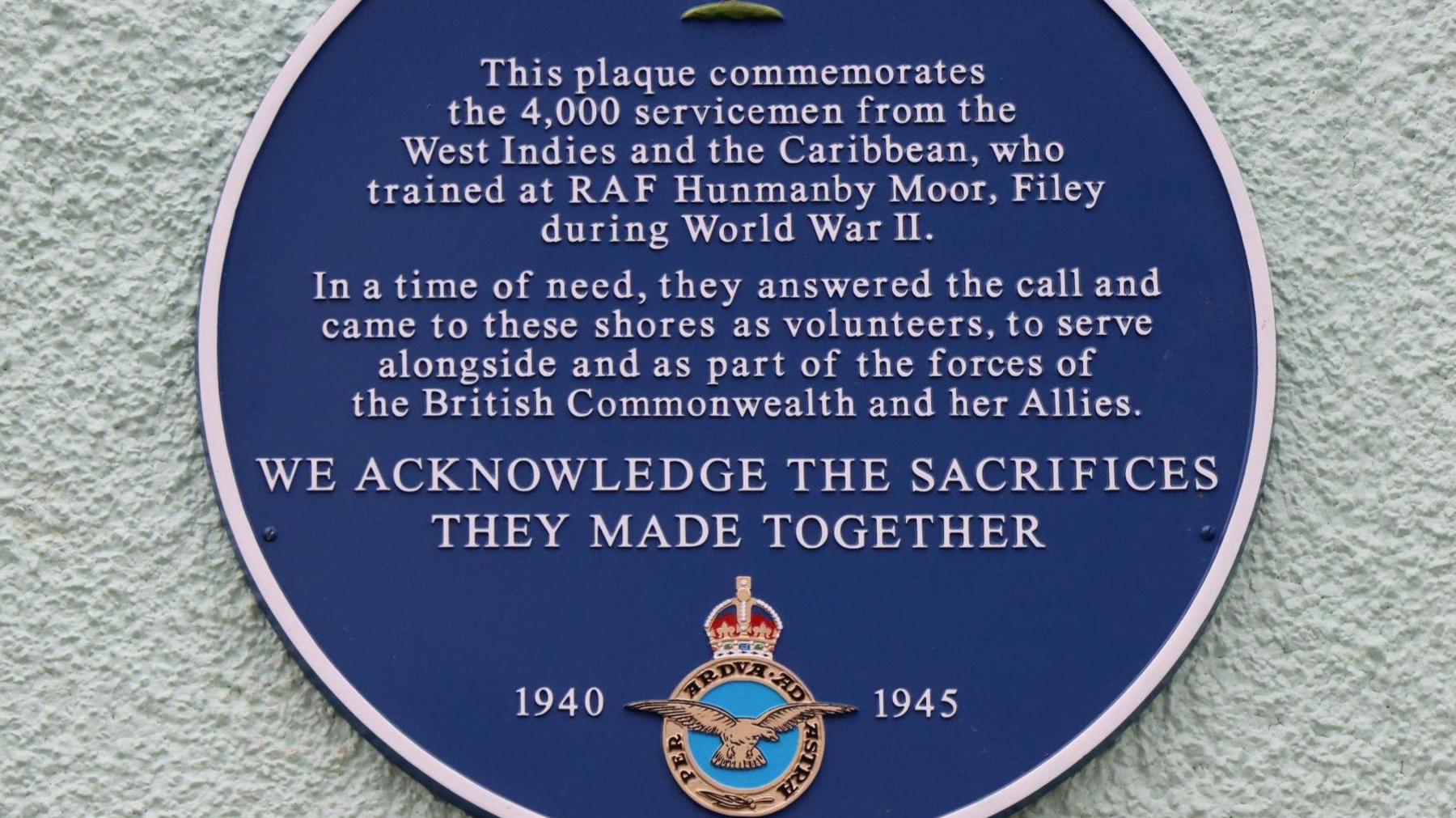 A blue plaque on a wall commemorating the service of 4,000 men from the Caribbean who served in the RAF during World War II and trained initially at RAF Hunmanby Moor near Filey