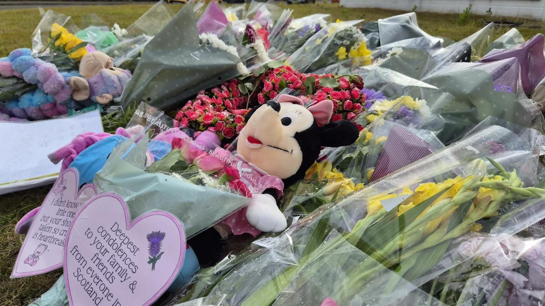 A Minnie Mouse toy sitting among floral tributes