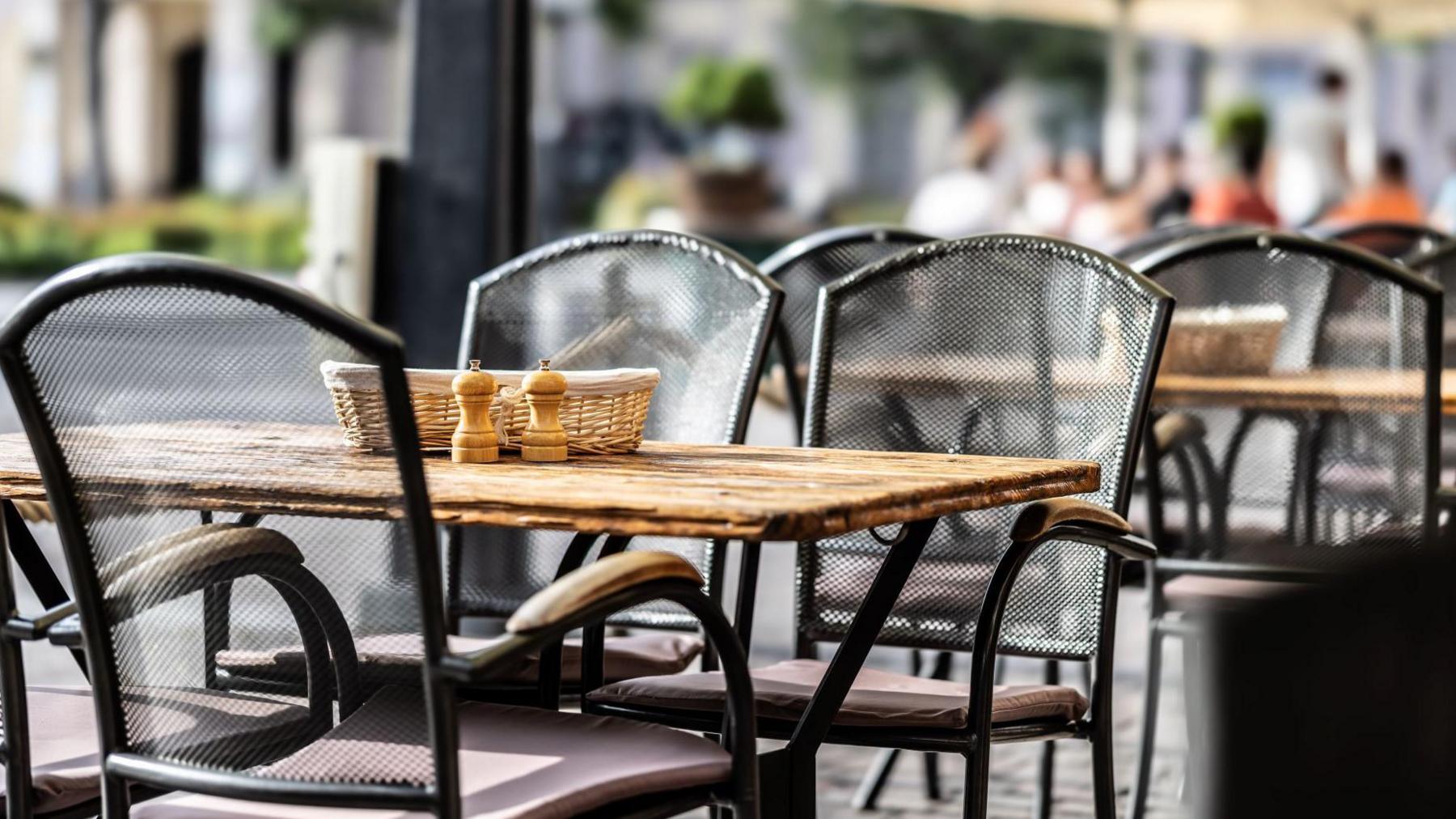 Outdoor tables and chairs. On the surface of none table is a basket and salt and pepper pots.