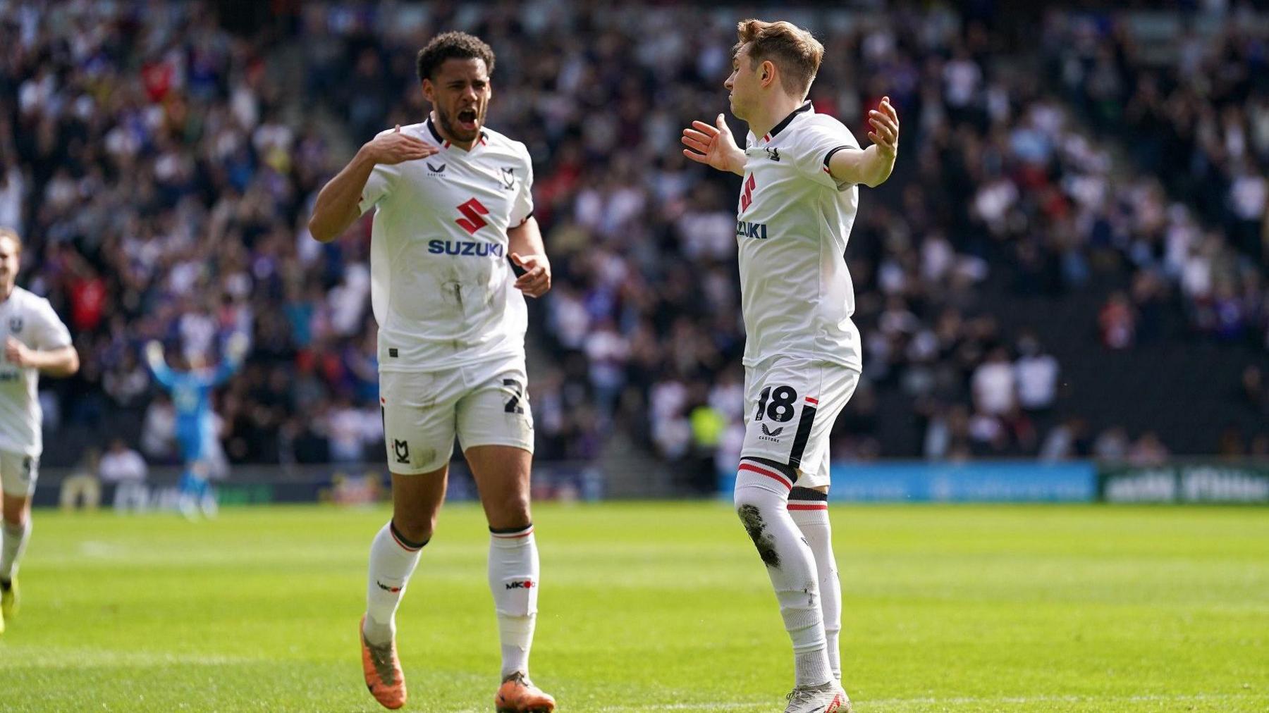 Two MK Dons footballers gesturing on the pitch