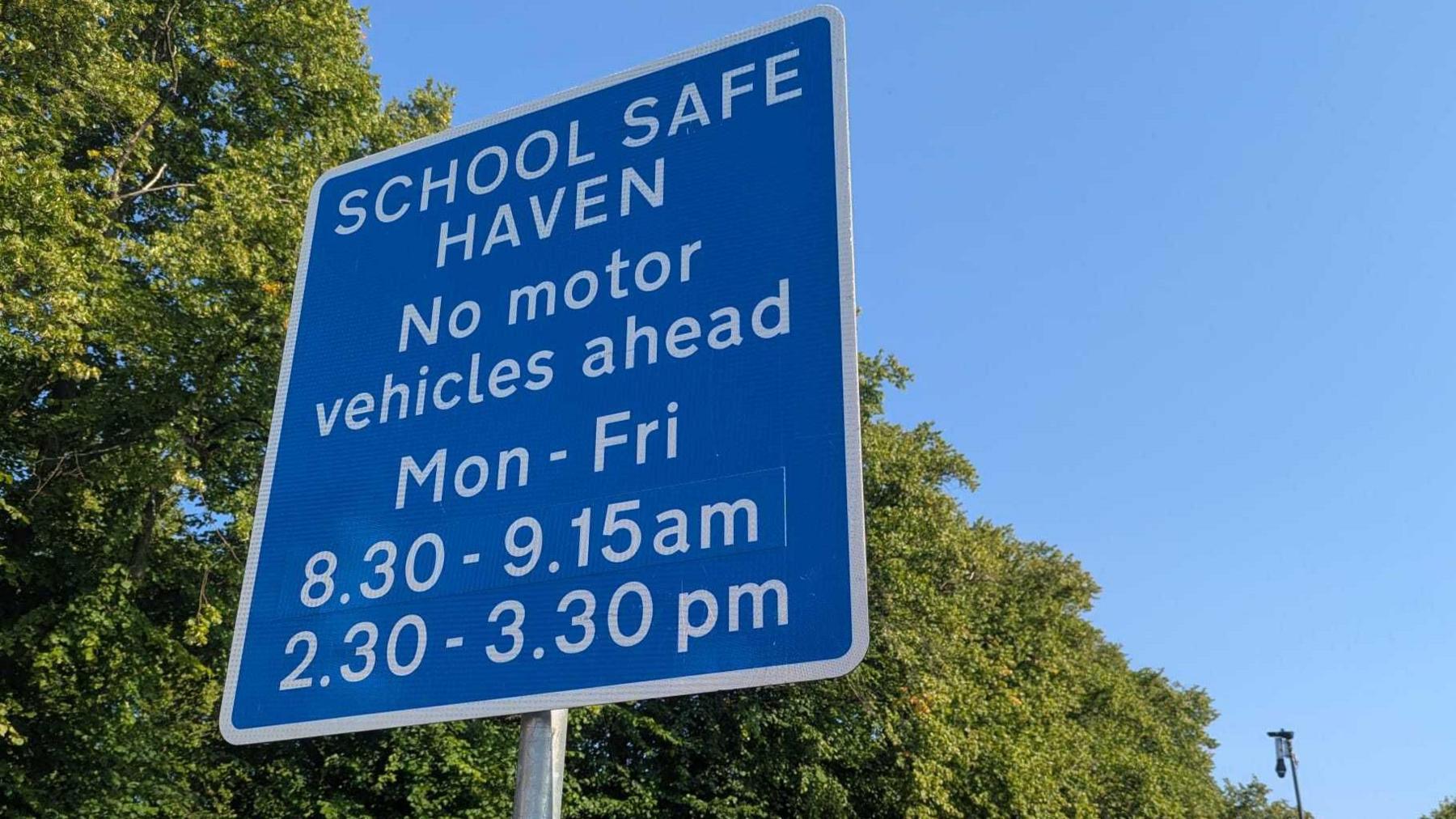 A sign which reads: SCHOOL SAFE HAVEN NO MOTOR VEHICLES AHEAD MON-FRI 830-915 230-330.