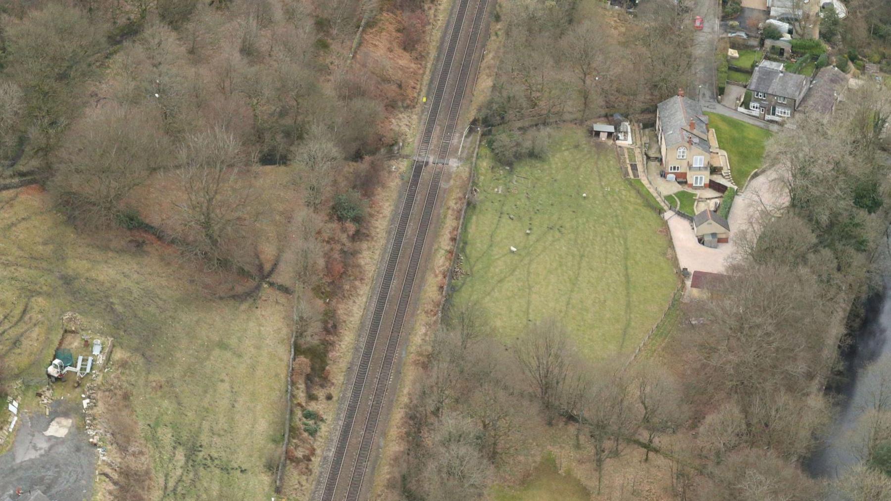 Aerial view of the railway track which includes the Moorgate Halt Crossing. It shows land and trees plus properties at either side of the railway line.