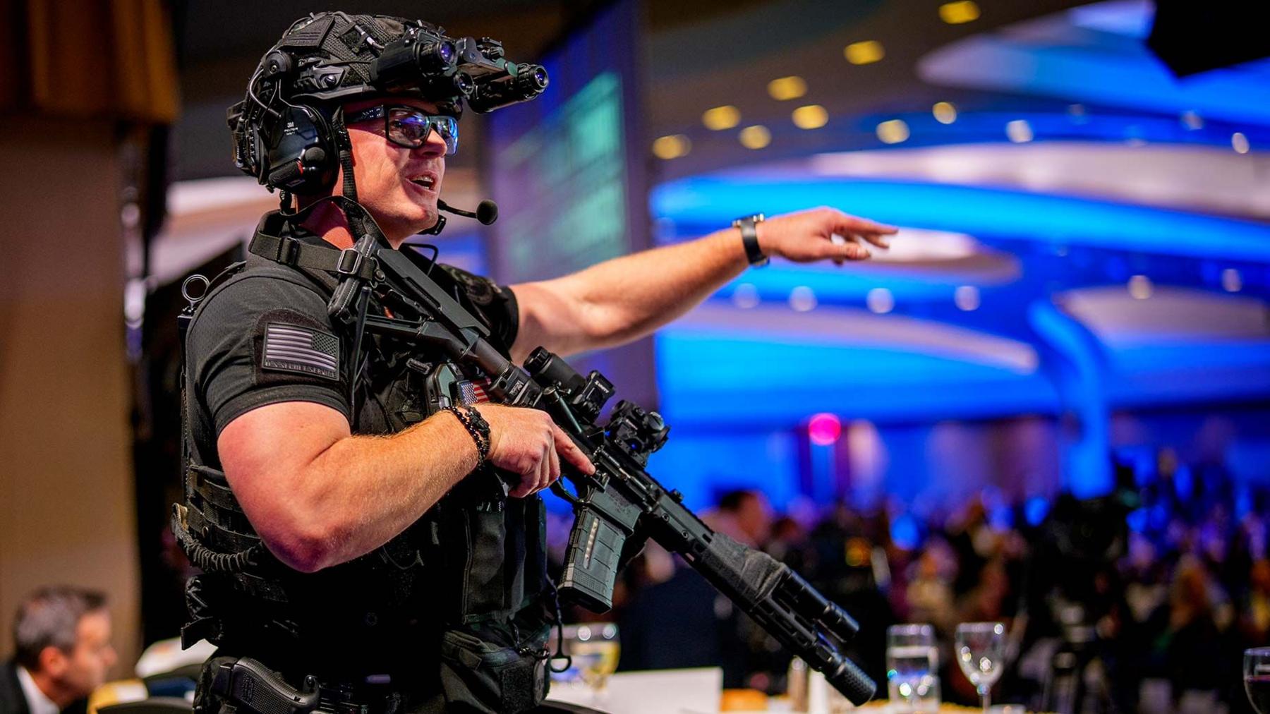 An armed Secret Service agent stands on stage following the shooting. He is dressed in black body armour and is heavily armed
