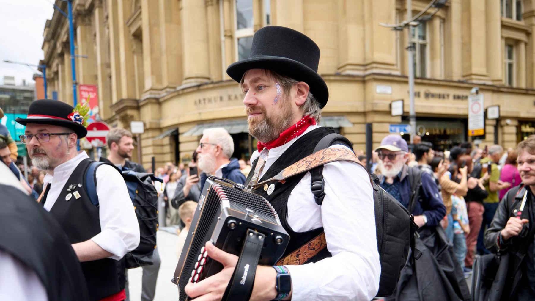 Morris band perfomer plays accordion in front of spectators