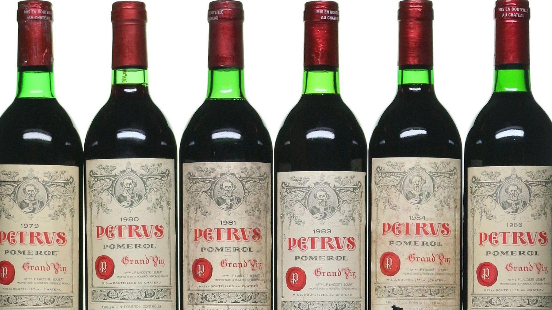 Green bottles of wine with red wax-sealed tops and the branding "Petrus"