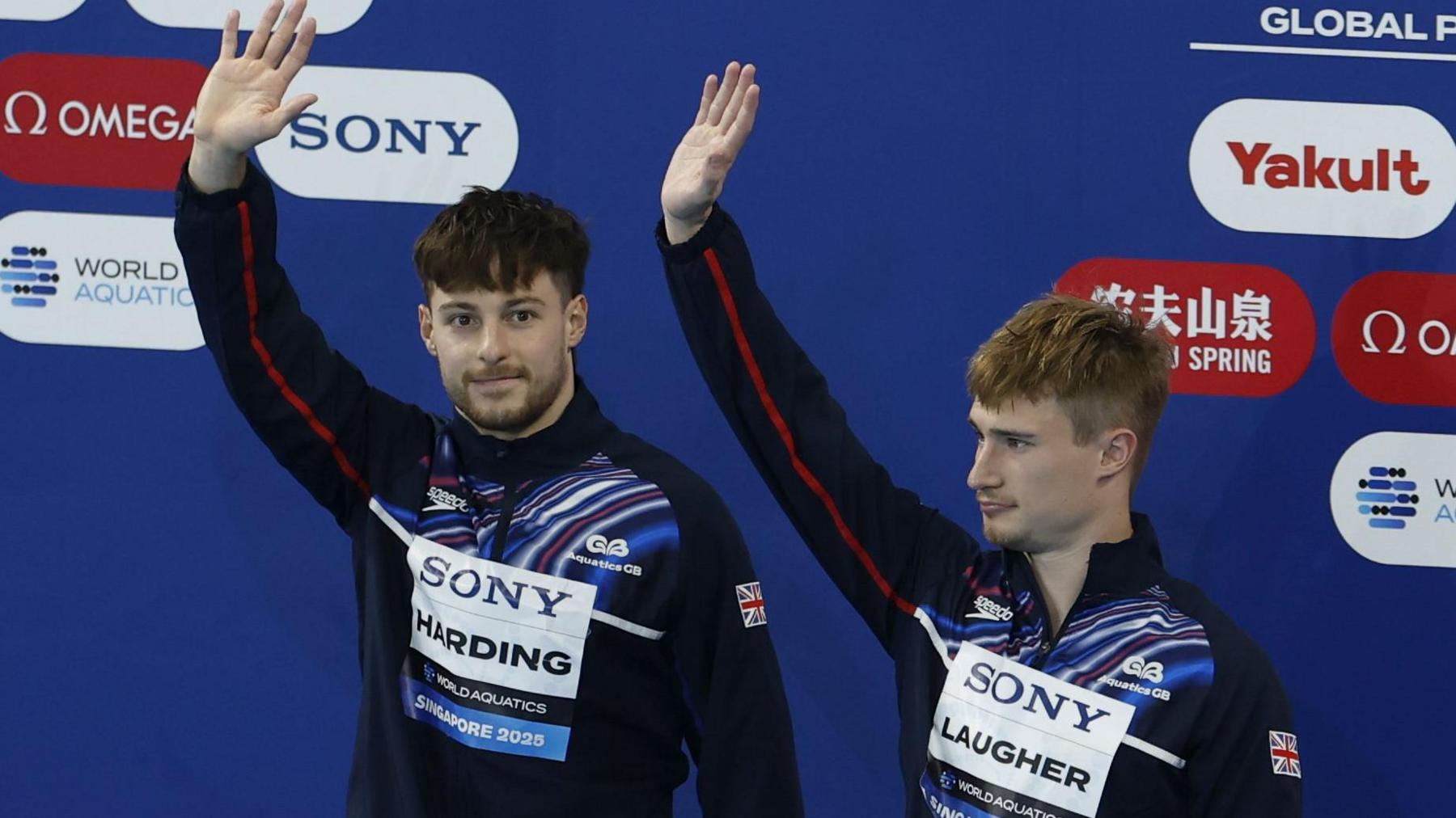 Anthony Harding and Jack Laugher wave while on the podium after winning bronze at the 2025 World Aquatics Championships