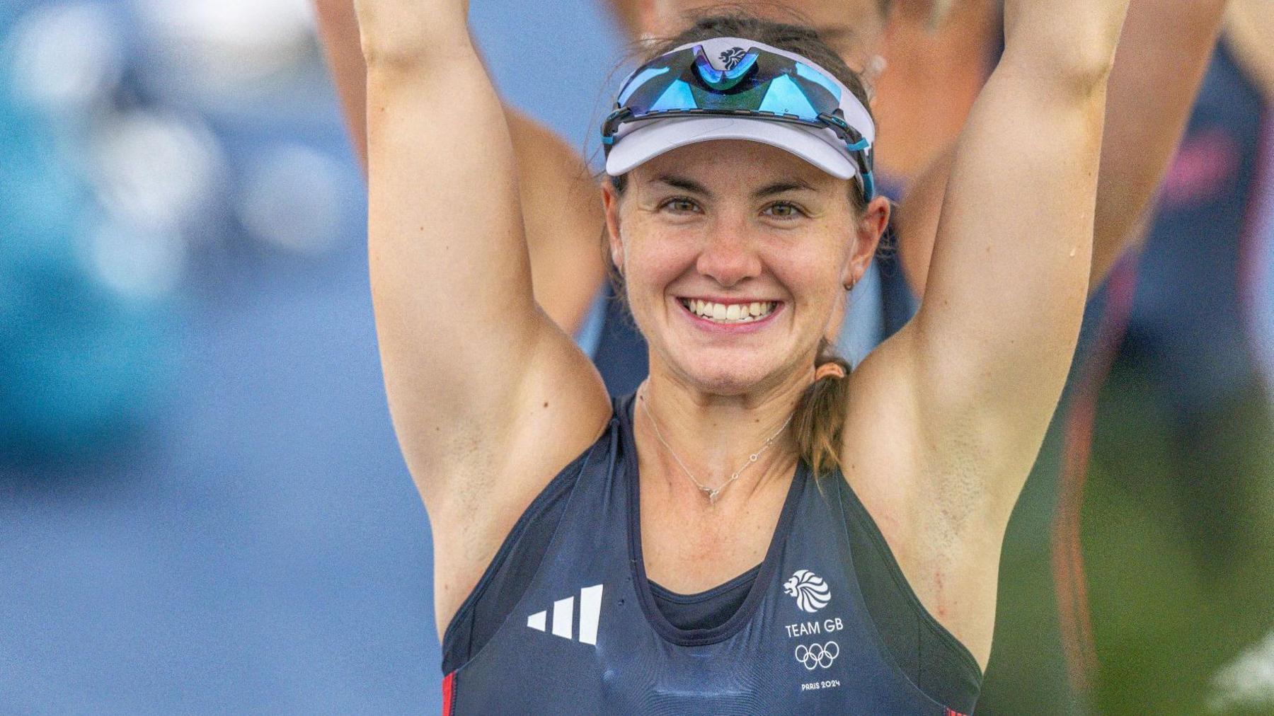 Lauren Henry with her arms in the air and wearing a cap and shades and a Team GB top at the Paris 2024 Olympics Games.