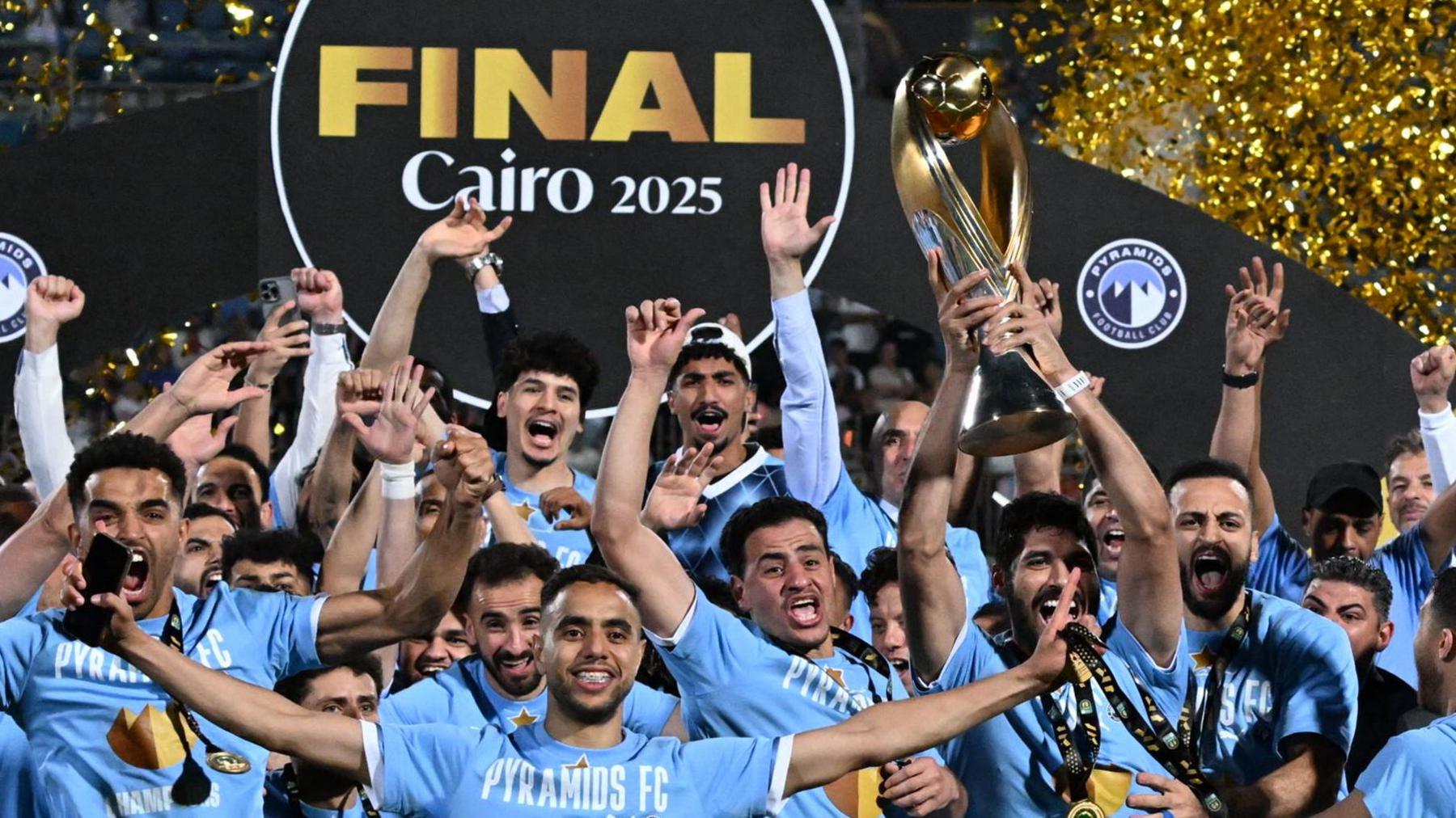 Pyramids players celebrate with the African Champions League trophy as golden ticker tape goes up in the background