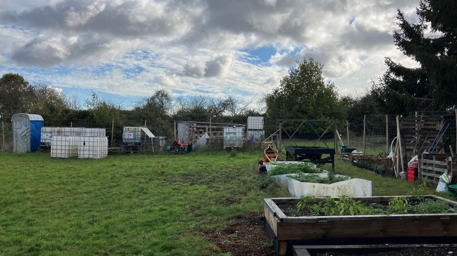 Plot of grassy land with raised beds and water carriers.