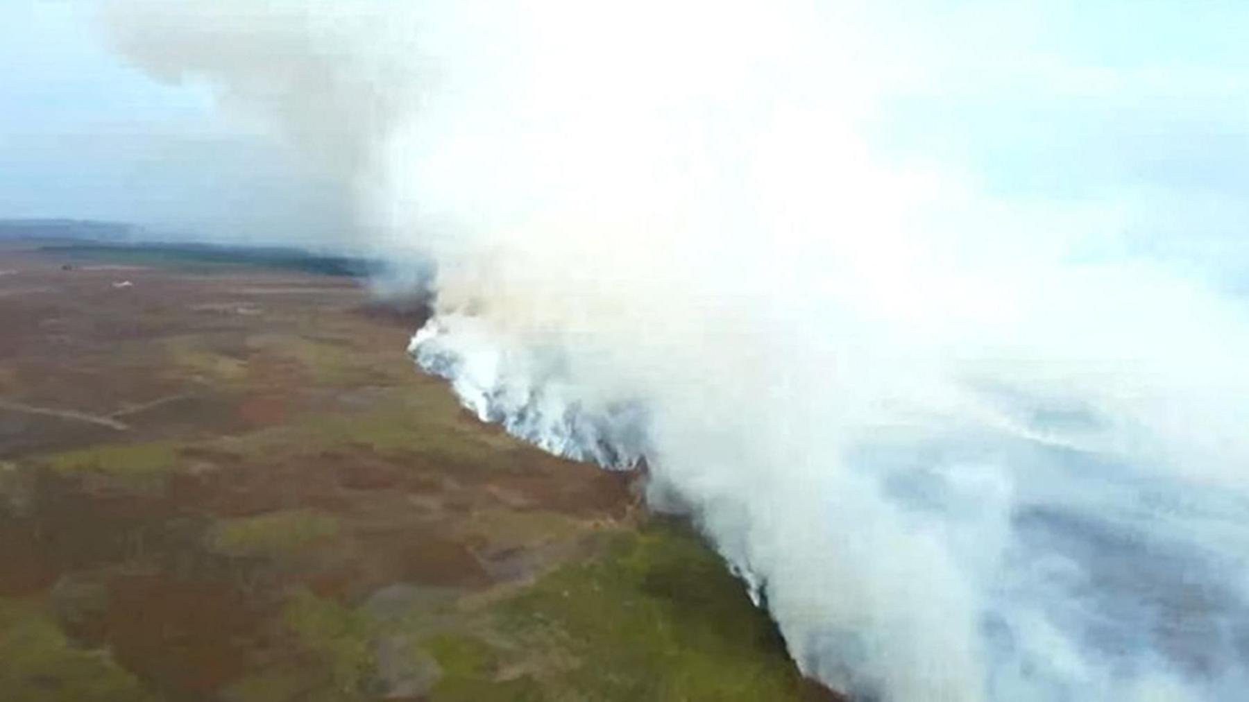 Smoke rises into the sky above burning moorland