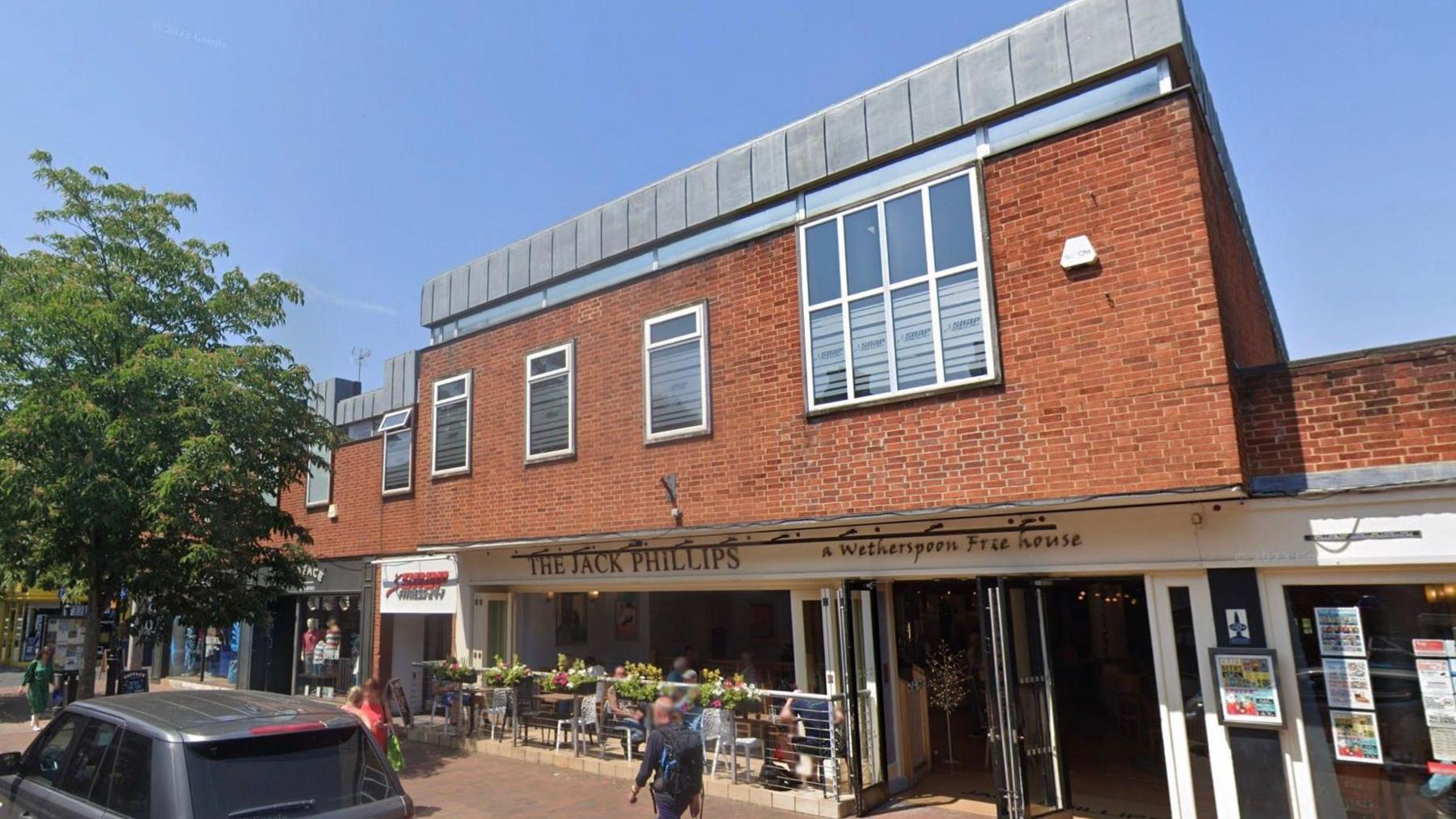 The Jack Phillips pub on the ground floor of a two-storey 1960s brick building.