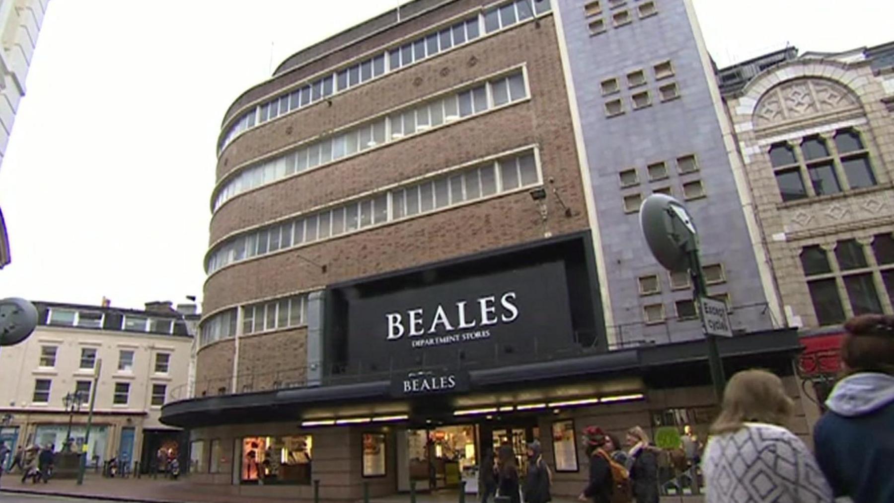 A large brick shop building with a large black sign with white writing saying 'Beales'