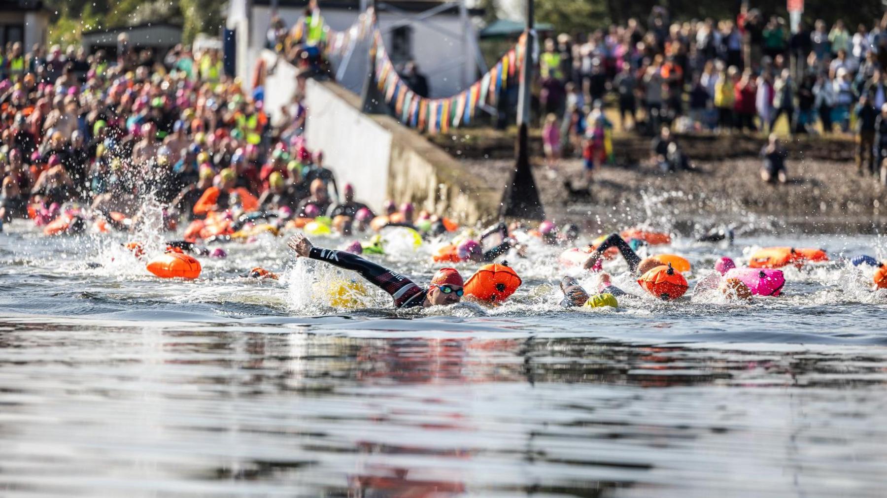 Swimmers in the water of the Kessock Channel with other swimmers and onlookers in background