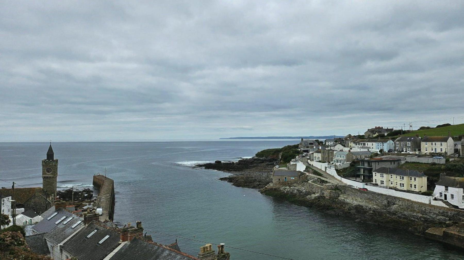 Buildings can be seen on either side of a harbour, with a harbour wall on the left near a clock tower. The sea and sky appear calm in this photo taken by Jerry.