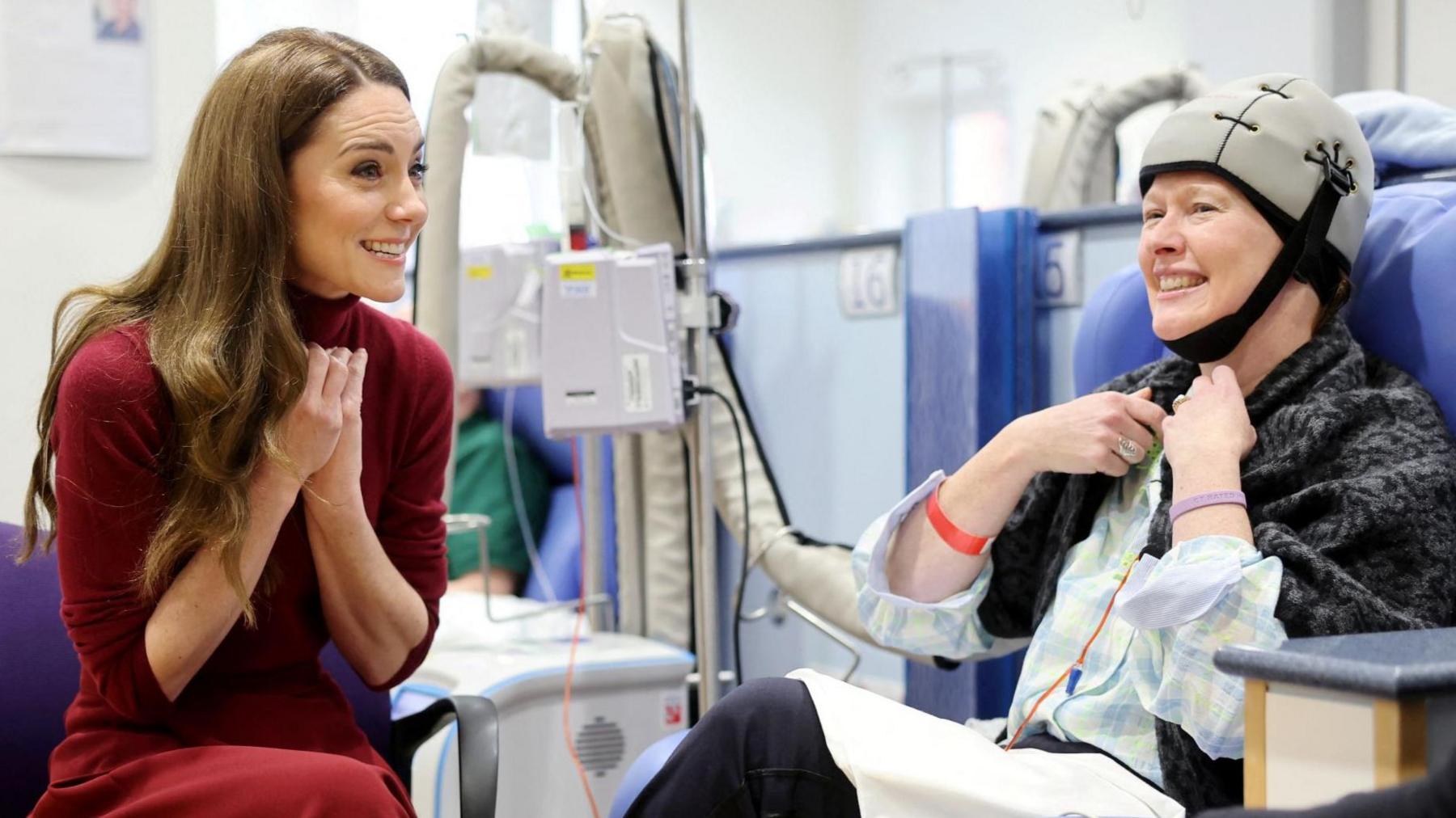 Catherine sits with a patient in a chair at Royal Marsden Hospital