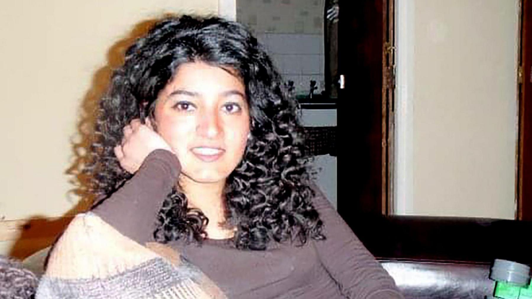 Zara Aleena, dressed casually with long curly hair spilling over her shoulders. She is sitting on a sofa and looks at the camera, seemingly mid-comment. She looks cheerful and engaged with the cameraperson.