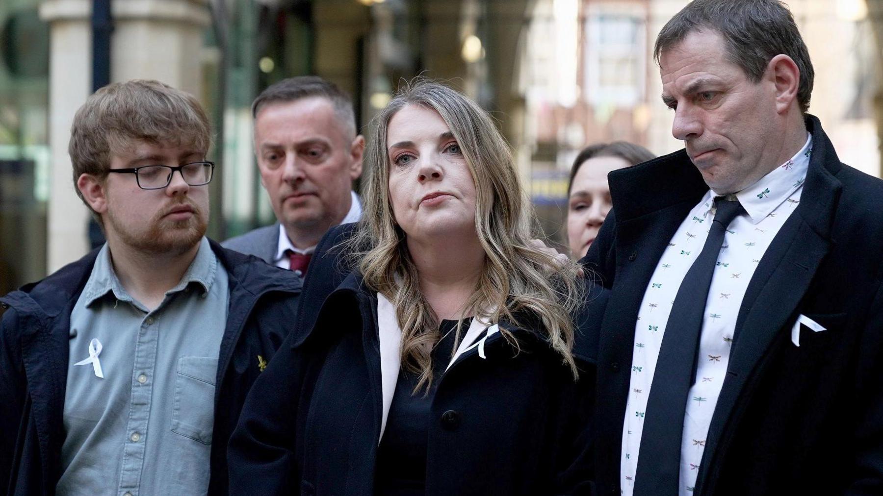 The family of Chloe Longster outside Northampton Coroner's court wearing navy suits and a white ribbon