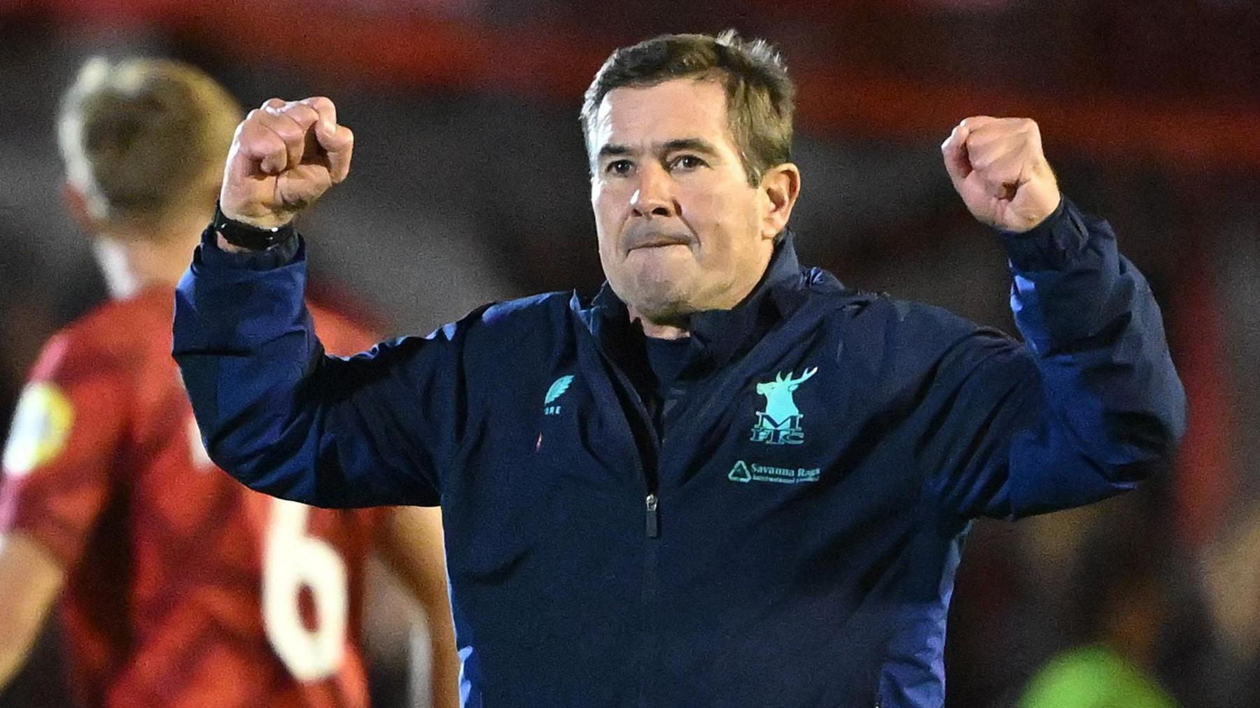 Mansfield Town boss Nigel Clough has both fists up in the air as he celebrates a win