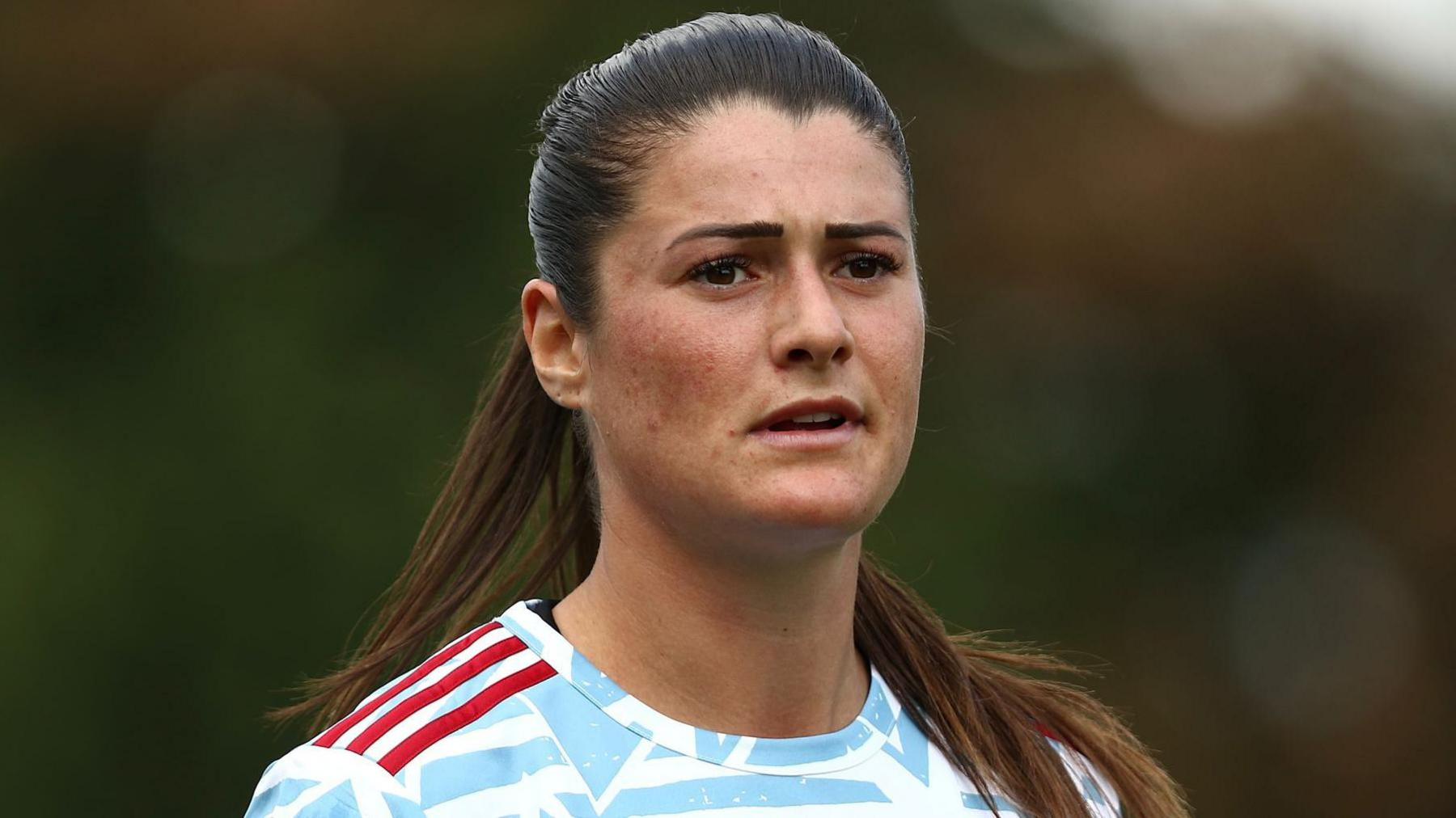 Holly Turner, wearing her Hashtag United jersey, which is patterned white and red. 