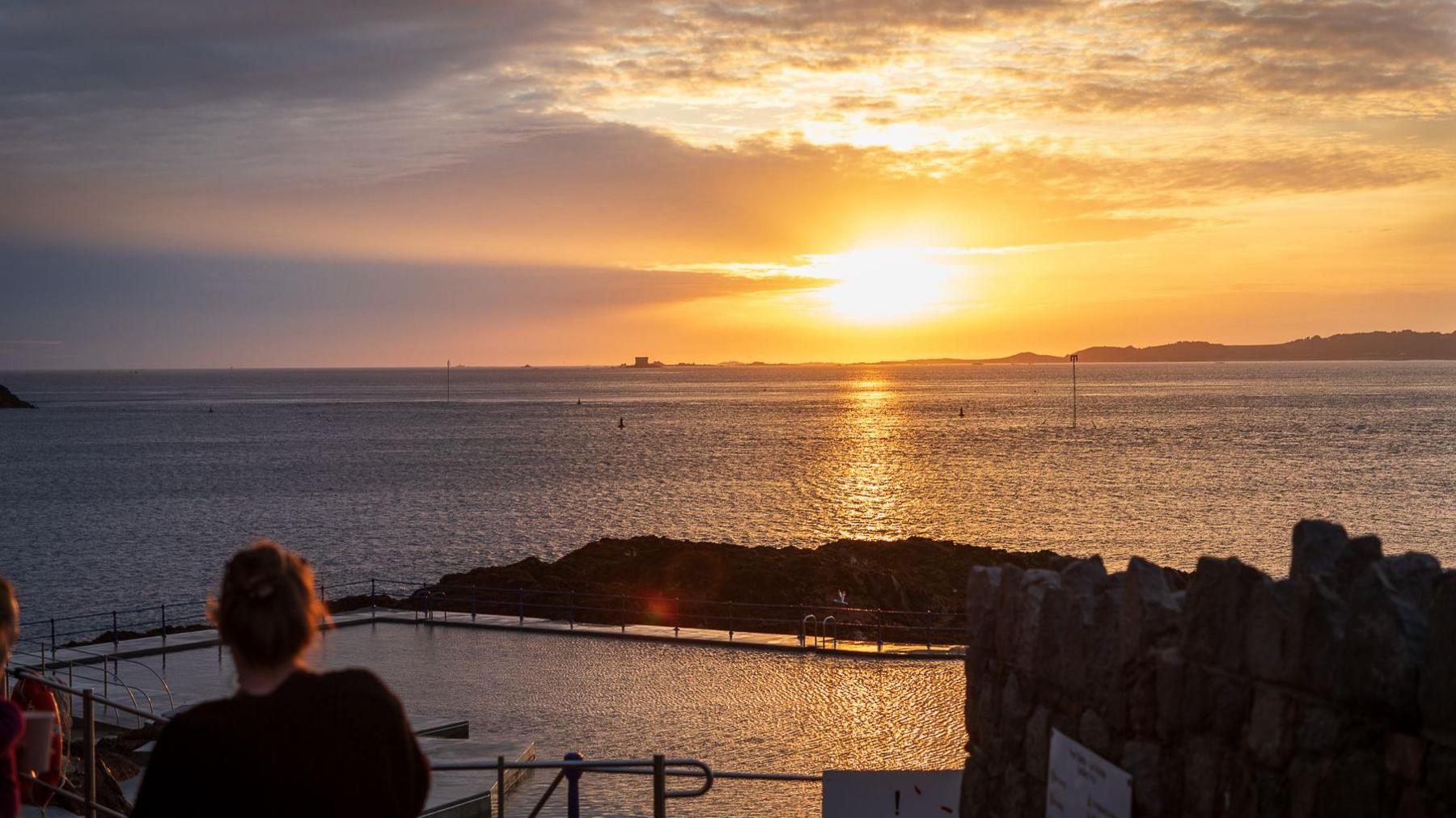 A woman watching the sun rise on Sunday morning