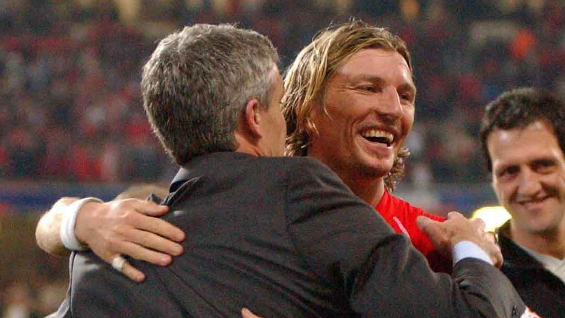 Robbie Savage in a red Wales shirt embraces suited Mark Hughes