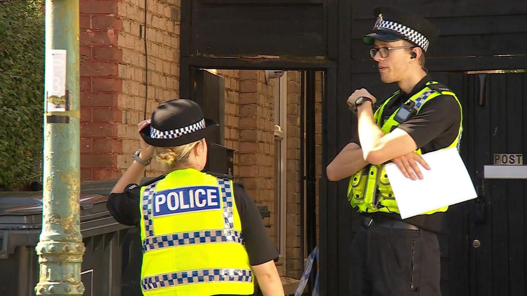 Two police officers outside Atkins flat