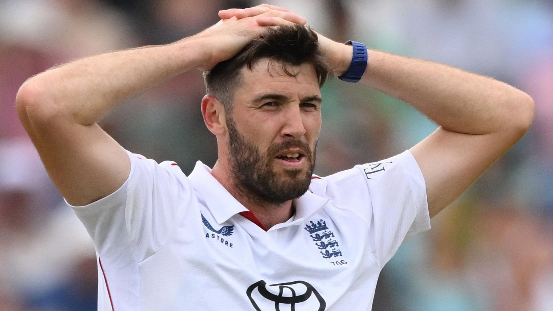 Jamie Overton, in Test whites, puts his hands on his head
