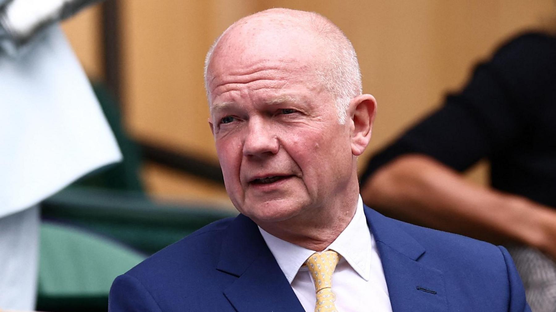 William Hague at a cricket match in suit and tie