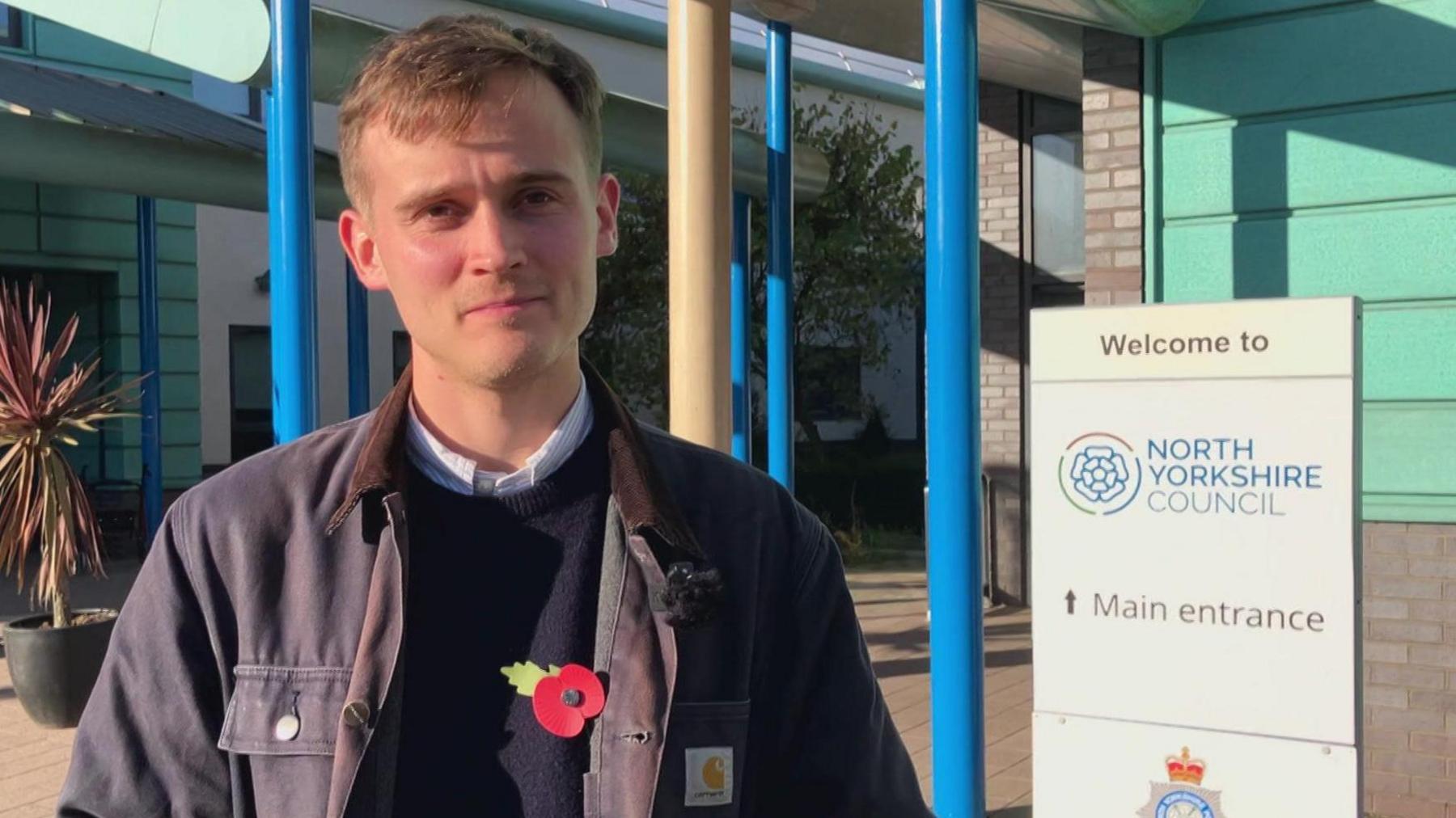 Keir Mather MP stands outside the Selby civic centre and council offices, looking into the camera with a neutral expression on his face.