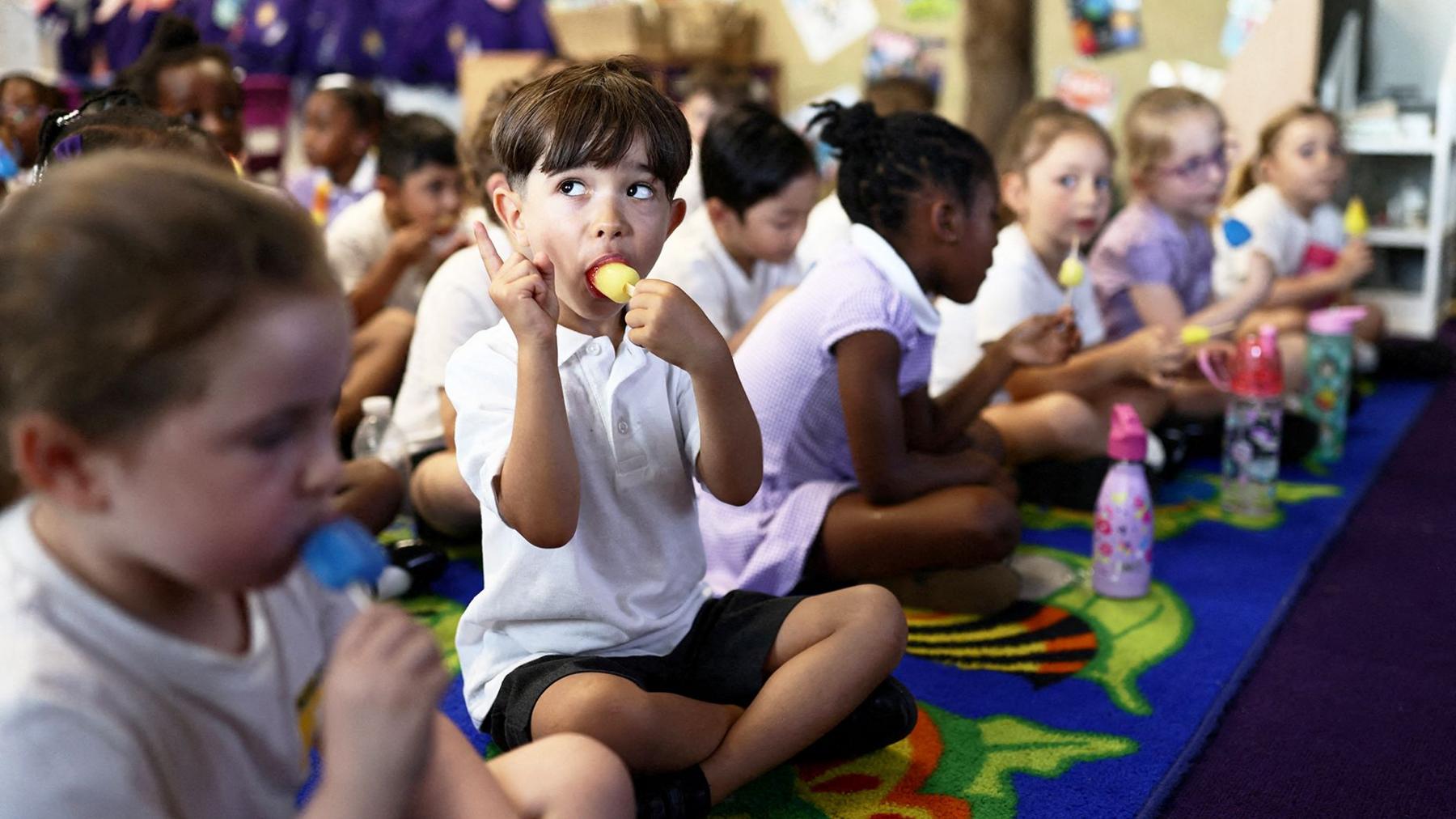 Pupils eat ice lollies as they attend a maths class at the Harris Academy Primary Mayflower school, as Britain experiences record temperatures disrupting schools and transport networks, in Grays, Britain, June 24, 2026. 