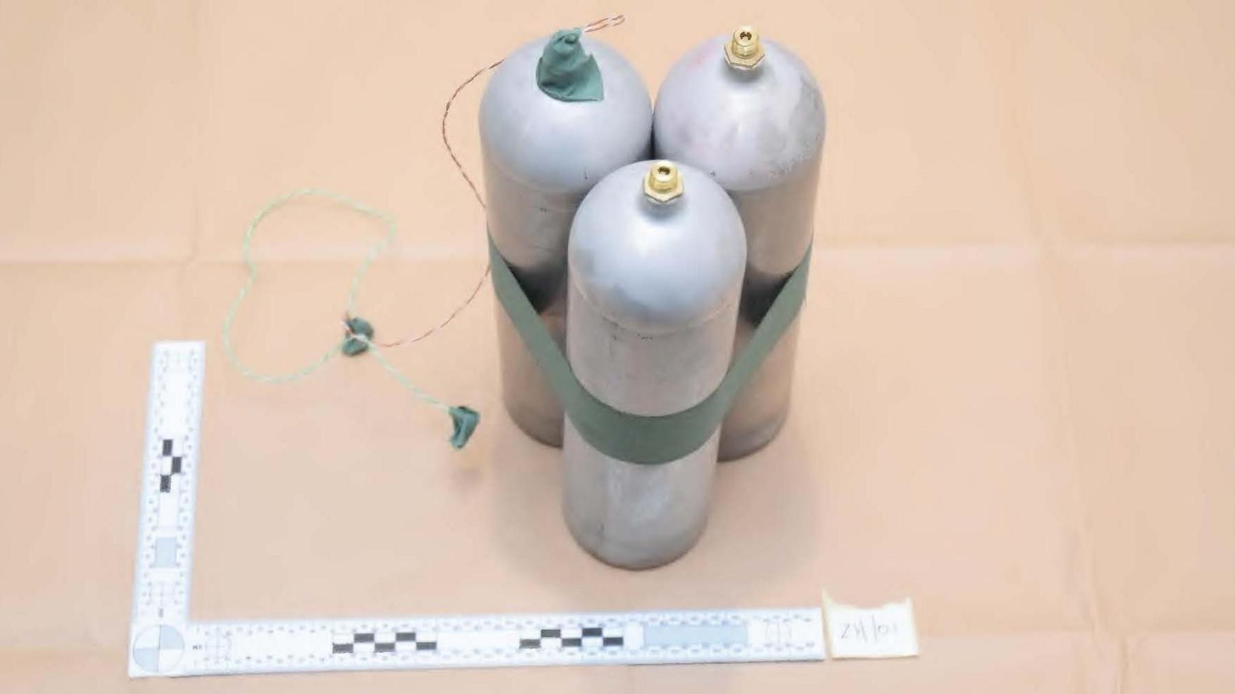 Three metal canisters, tied together with green tape and with what appears to be a wire hanging off the top of one, in a police evidence photo 