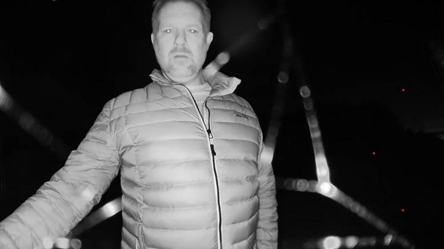 The photo is taken from a doorbell security camera. It shows a man, Paul Whitehurst, in a puffa jacket. He is ringing the bell.