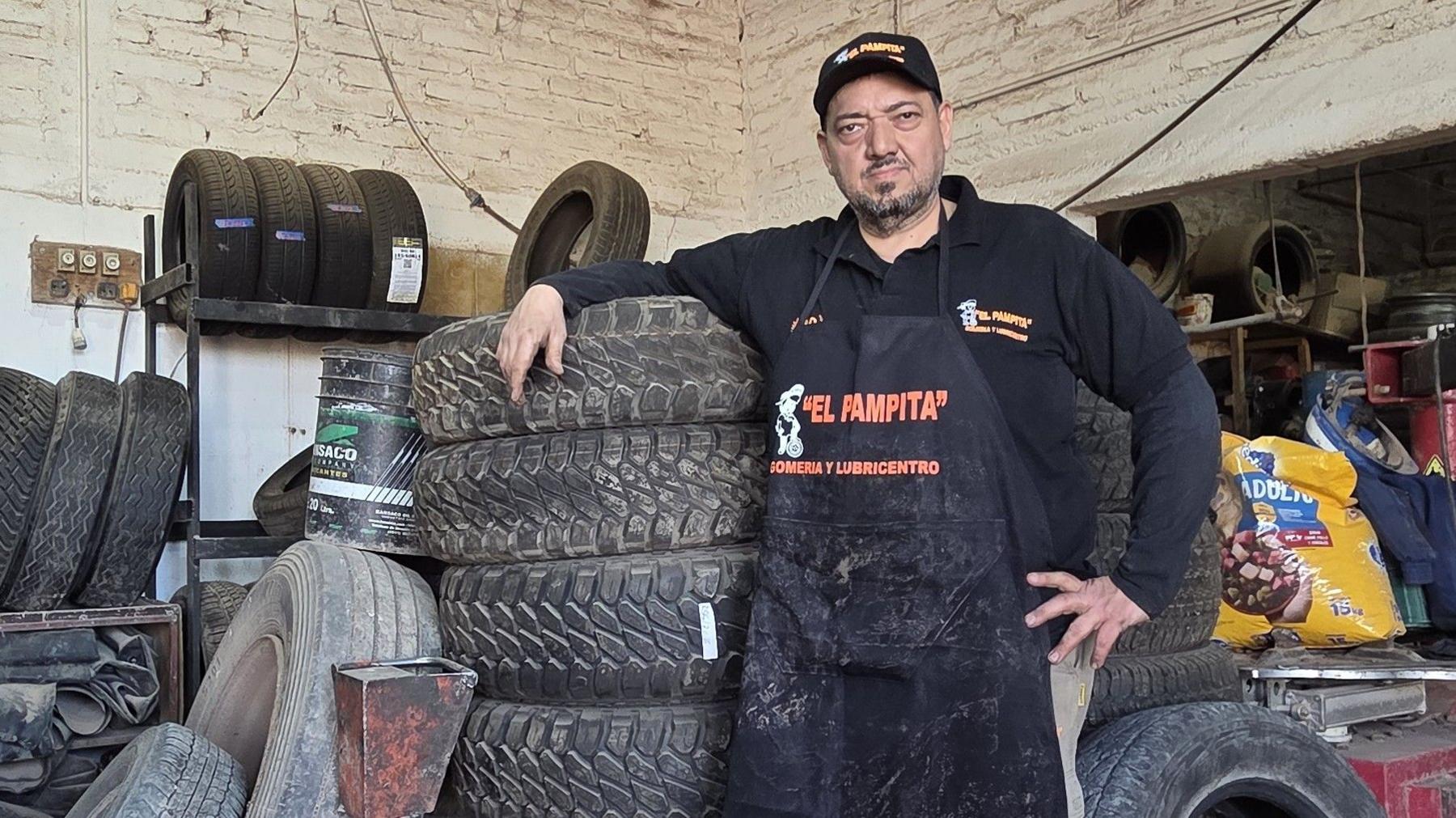 Mechanic Fabio Javier Jiménez leaning on tyres at his garage